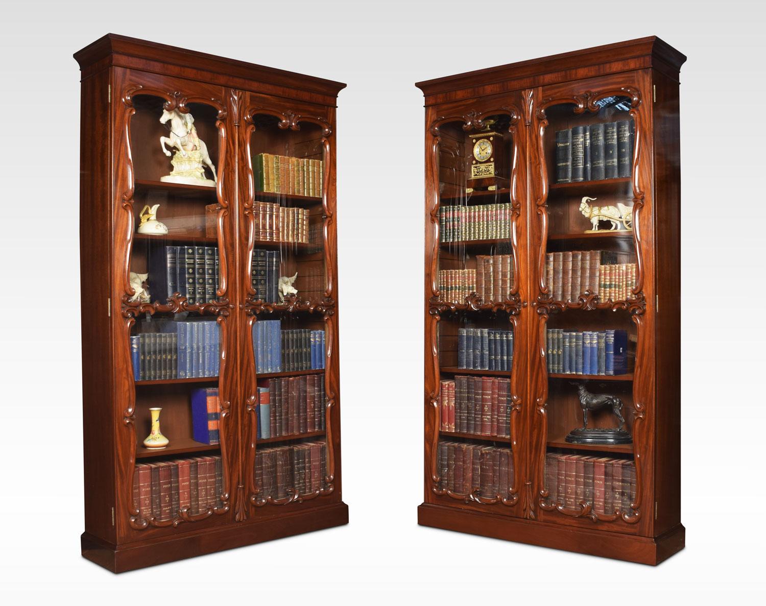 Pair of mahogany bookcases the moulded cornice above a pair of large glazed doors opening to reveal six adjustable shelves all raised up on conforming plinth, adapted from a larger bookcase.
