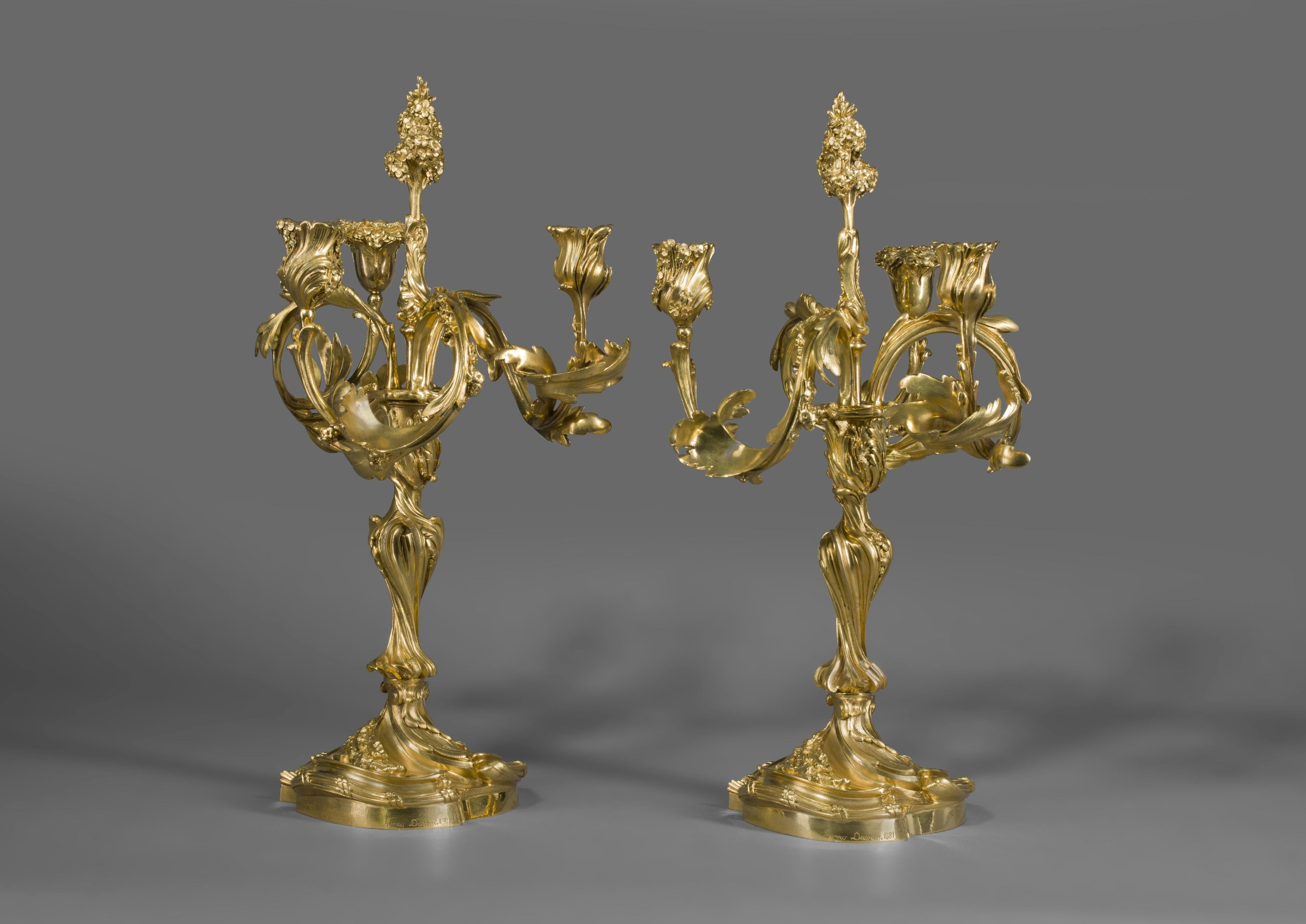 A fine pair of Rococo Revival gilt bronze three-light candelabra in the manner of Juste Aurèle Meissonier, by Henry Dasson.

French, dated 1881.

Signed to each base 'Henry DASSON' and dated 1881. 

Each candelabra is modelled with stylised