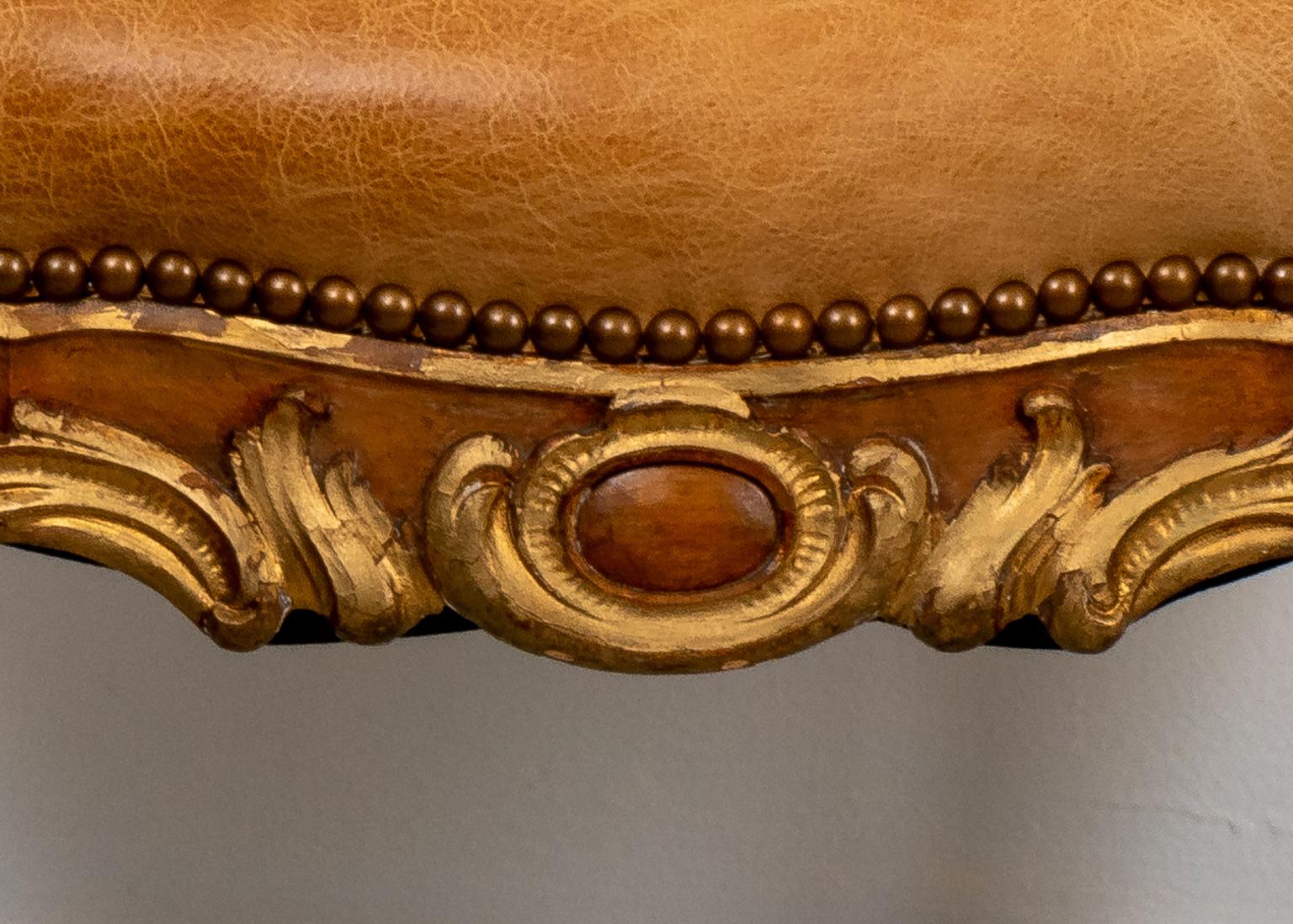 Circa 1900s pair of Italian Rococo style footstools with pegged construction, newly upholstered in leather with dark wood on the legs and lighter wood on the apron. The piece also features slight cabriole legs with carved knees and apron detailed