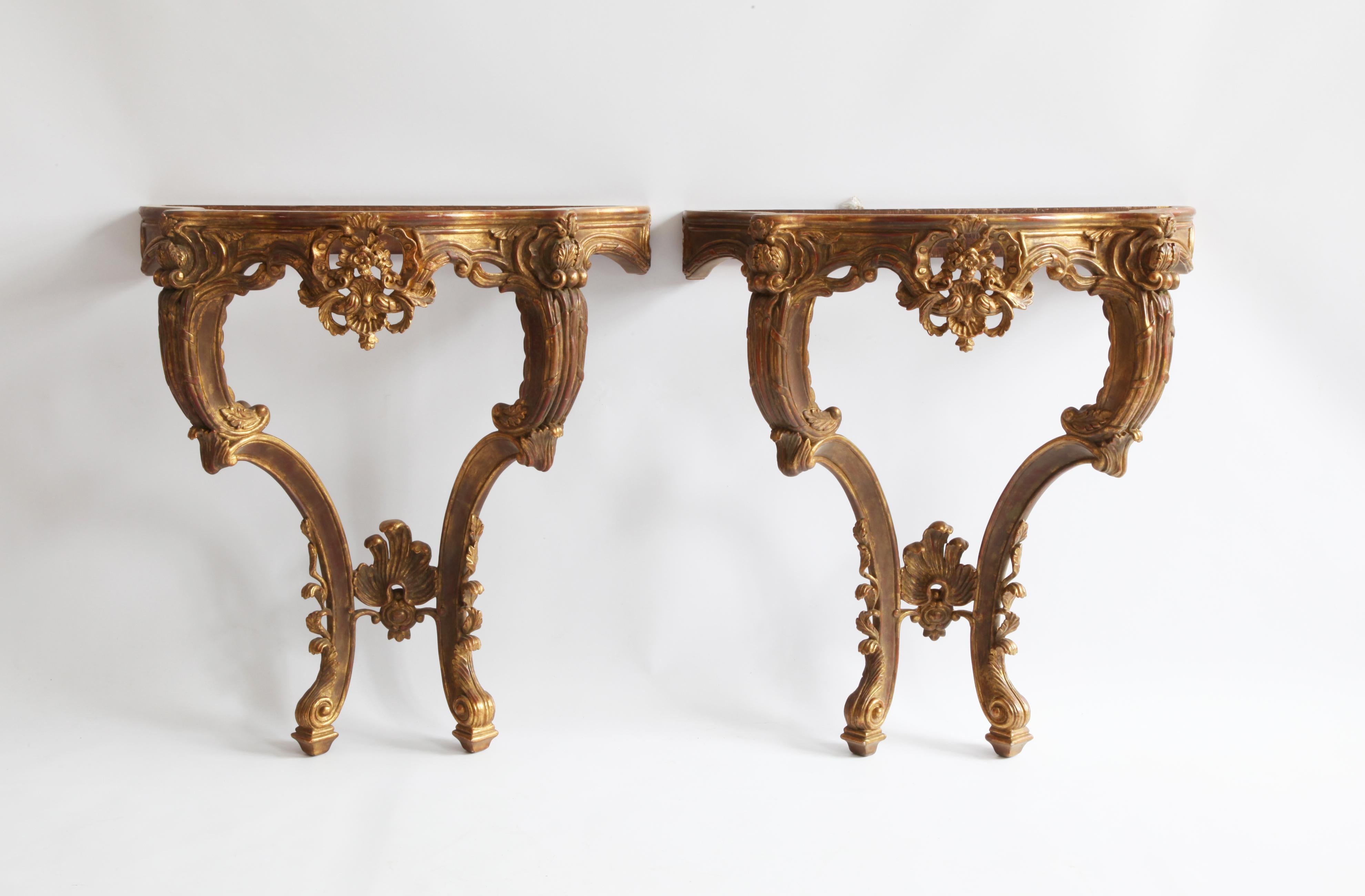 Pair of Rococo style consoles: Hand-carved by master craftsmen and finished with an antique gilded patina using traditional methods and materials. 

We have a selection of marble to choose from. (prices on request)