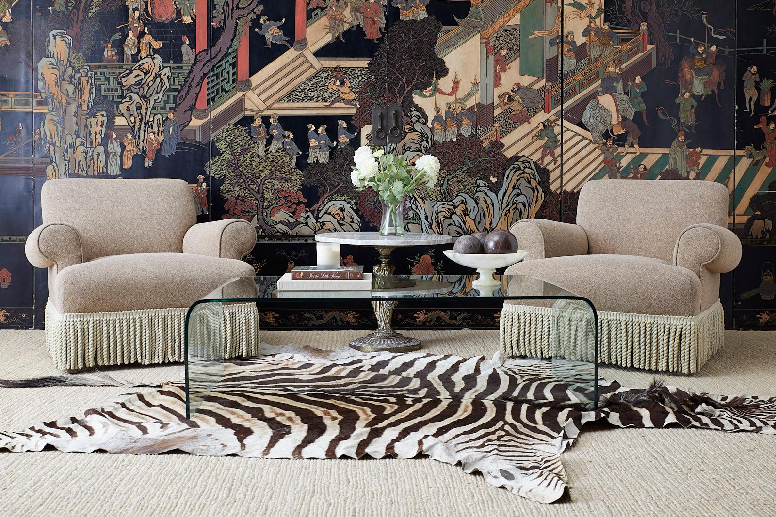 Bespoke pair of large upholstered club chairs or armchairs featuring a textured fabric and thick bullion fringe. Excellent joinery and craftsmanship supported by four upholstered legs. From an estate in Beverly Hills, CA.