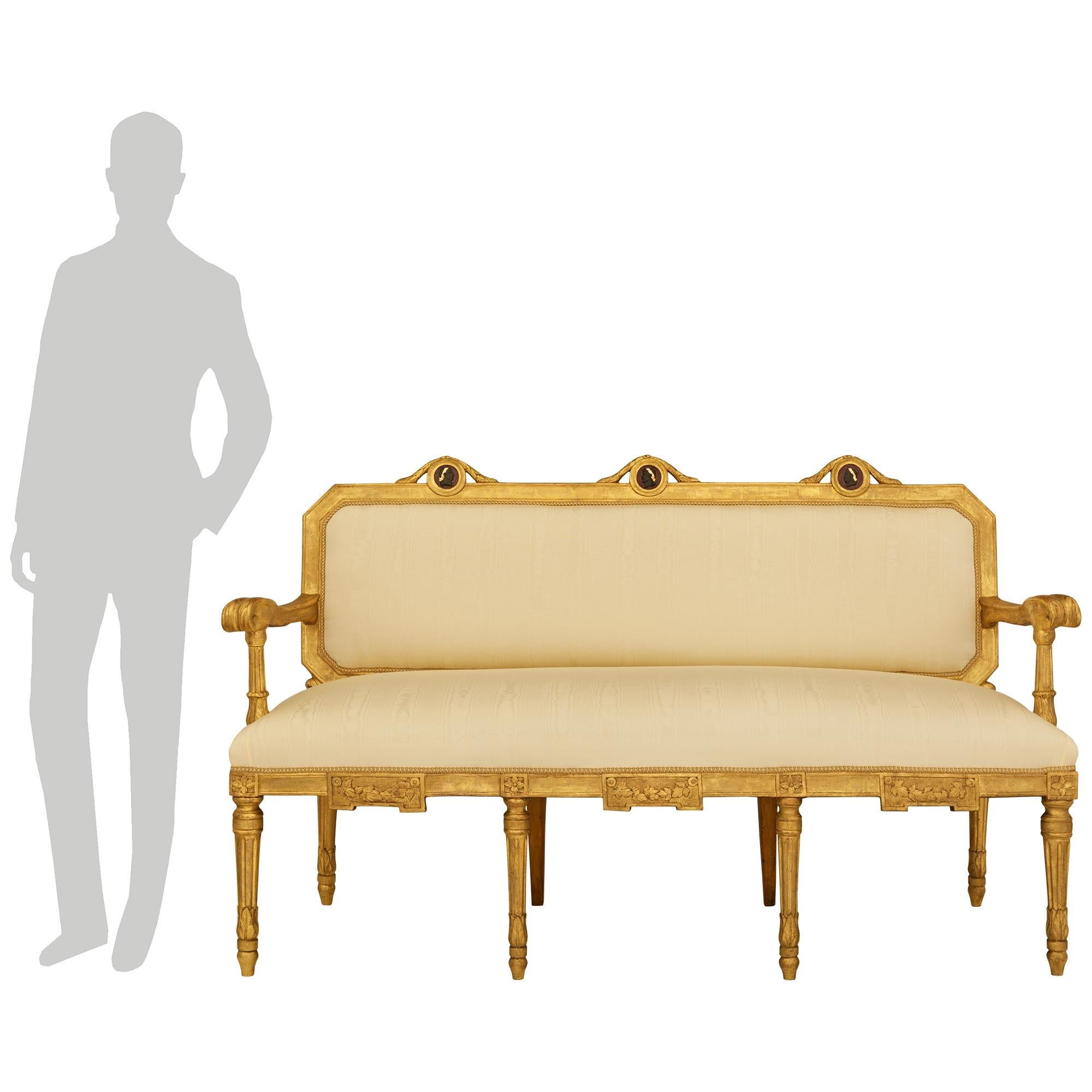 Une paire majestueuse et très décorative de canapés romains en bois doré d'époque Louis XVI du XVIIIe siècle. Cette magnifique paire de canapés repose sur huit pieds en forme de toupie en bois doré, avec des colliers feuillagés menant à des pieds