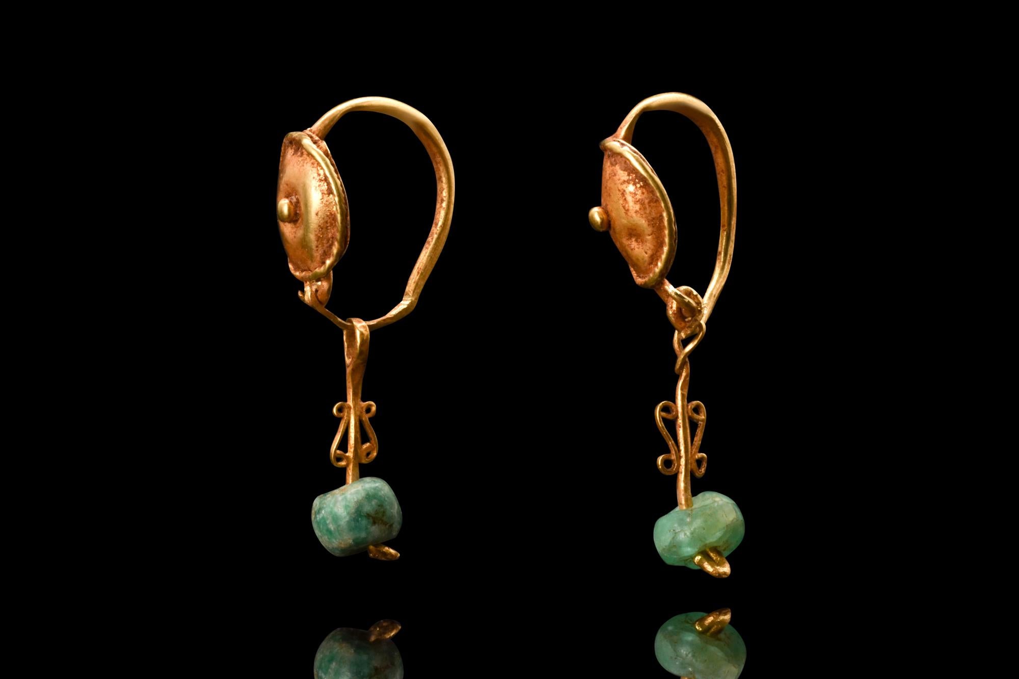 A lovely pair of Roman gold earrings comprised of a delicate hoop, secured with a hook and eye closure, and adorned with a boss shield. The shield features a twisted border and a central granule, adding a refined touch to the earrings' overall
