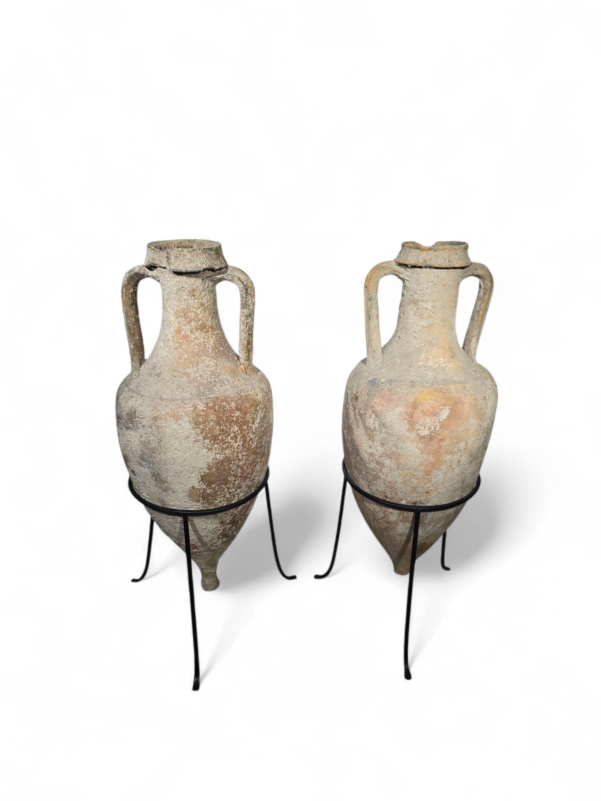 Impressionante coppia di anfore romane in terracotta risalenti al III-I secolo a.C., montate su basi in ferro personalizzate.
Queste anfore venivano tradizionalmente utilizzate per conservare il pesce salato e altri alimenti conservati, una pratica