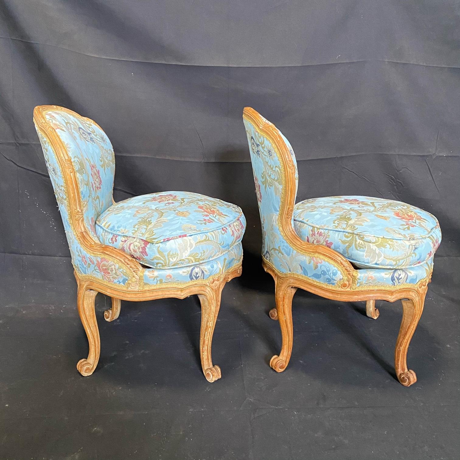 19th century French Louis XV style slipper chairs having rounded carved backs connected to seats raised on four cabriole legs with scrolled acanthus leaves on the apron carved in the front. Recent immaculate high end silk upholstery is an eye