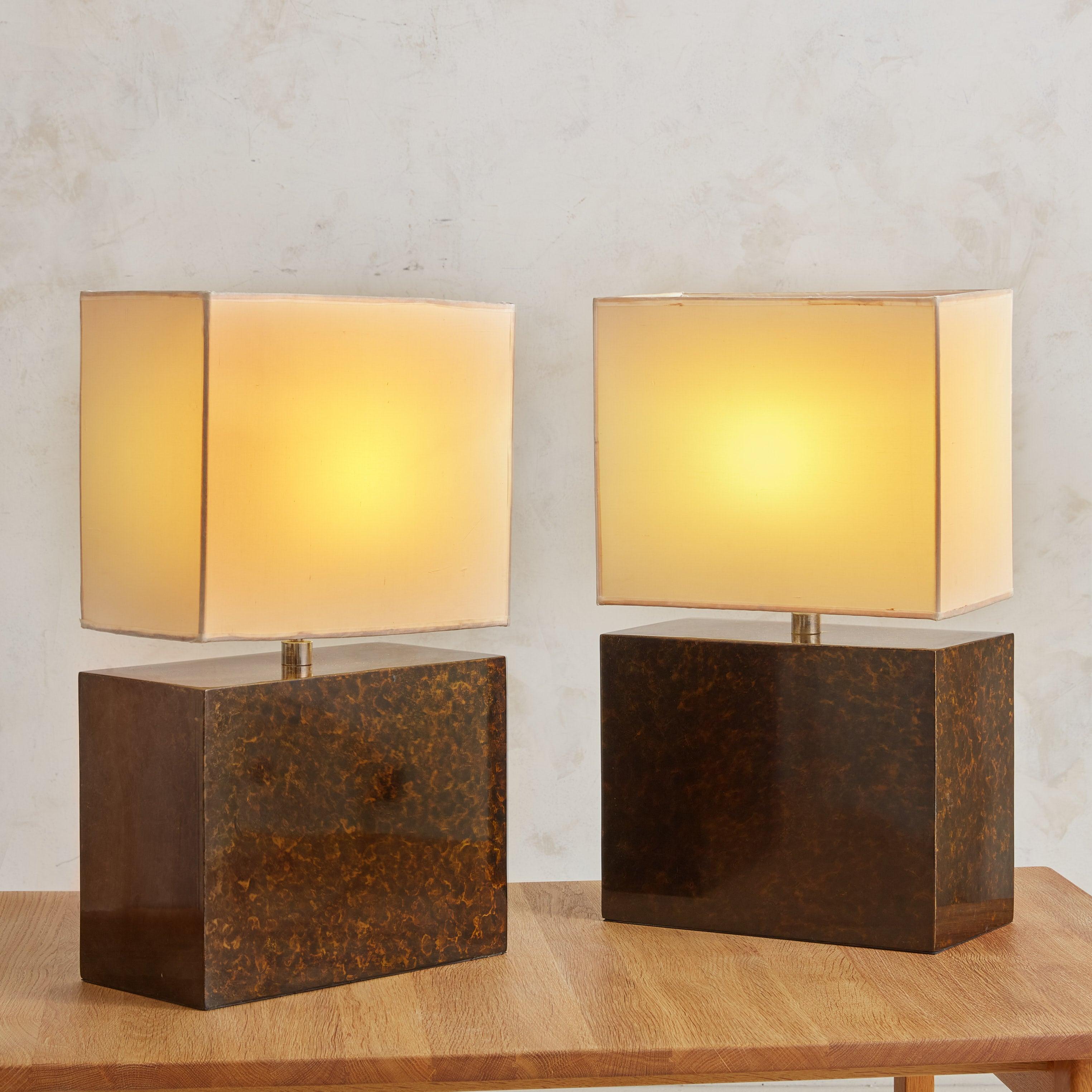 Paire de lampes de table françaises modernes du milieu du siècle dans le style de Romeo Rega. Ces lampes sont dotées d'un socle rectangulaire en bois recouvert d'une couche de parchemin et d'une finition laquée, créant un effet marbré époustouflant