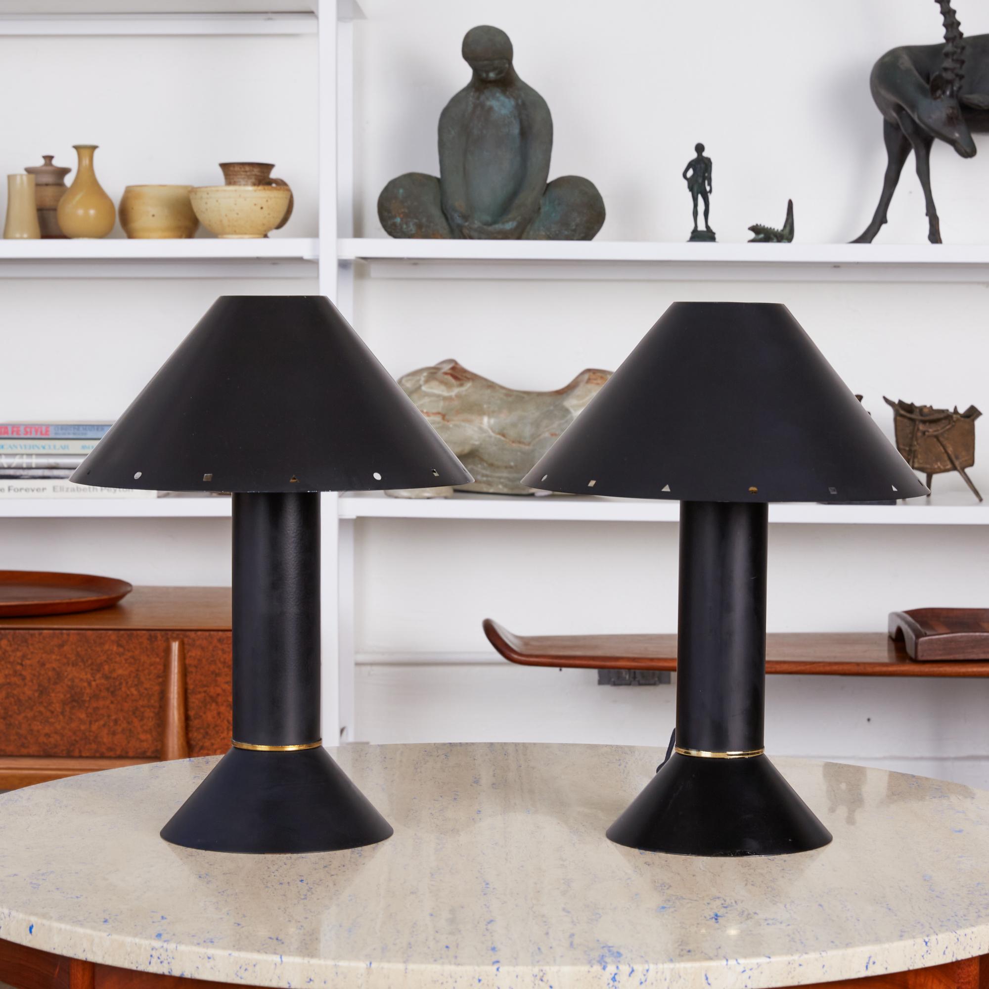 Pair of Postmodern table lamps by Los Angeles lighting designer Ron Rezek, circa 1980s. The lamps feature a black metal frame and removable black shade with polished brass ring accent that sits at the bottom of a cone shaped base. The shade features