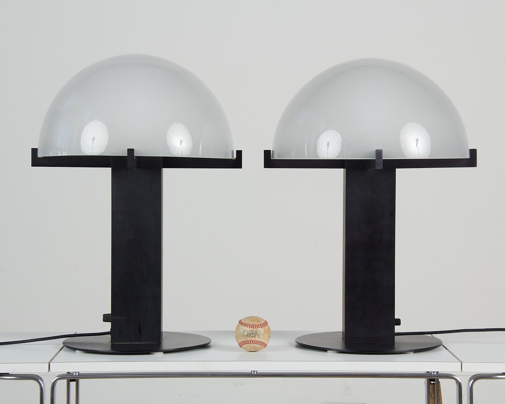 Postmodern table lamps by Los Angeles lighting designer Ron Rezek, c.1980s. The lamps feature a black metal frame and removable glass dome shades. The shades features a frosted glass. The shade is removable and sits atop a fixed metal prong setting.