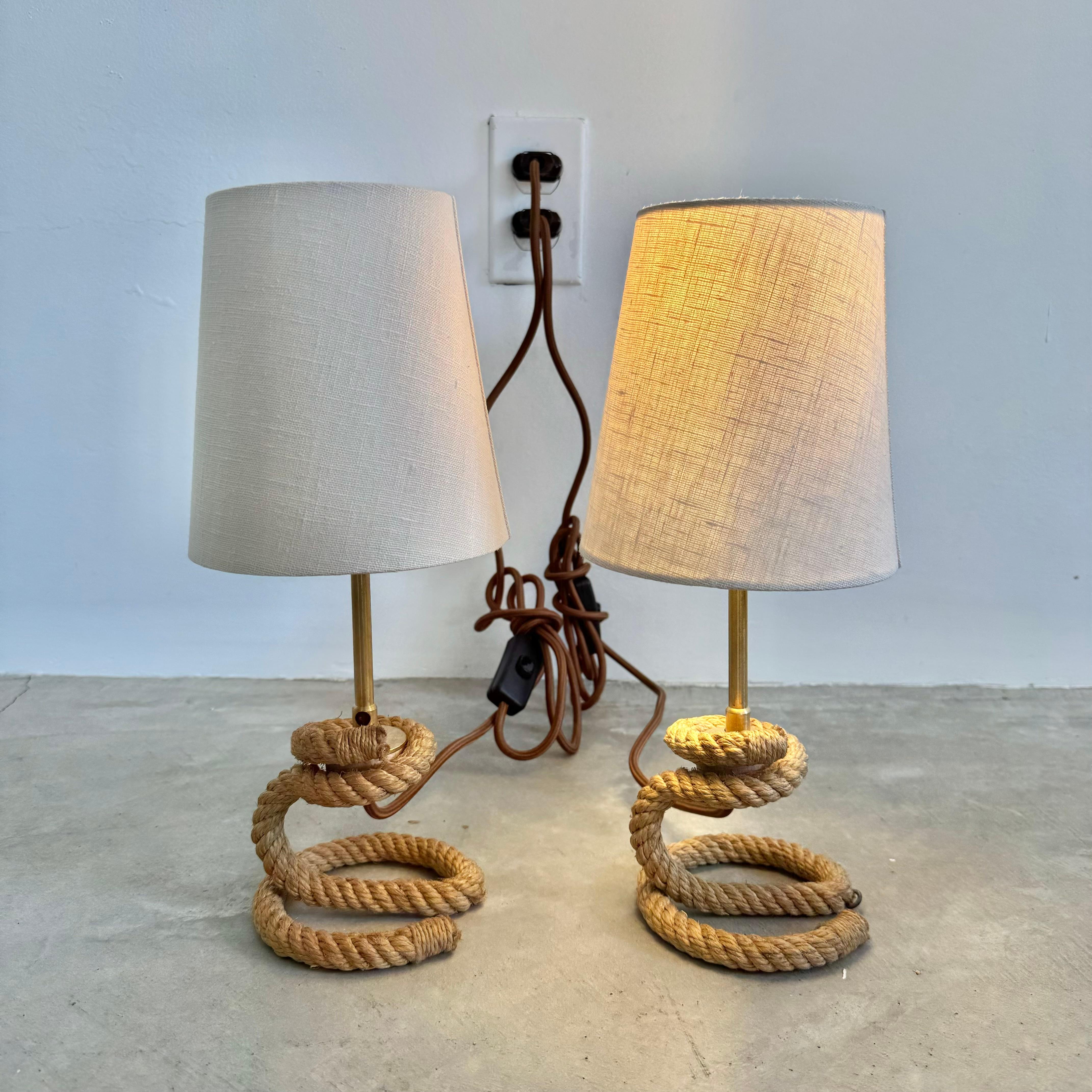 Sculptural pair of table lamps in twisted rope in the style of French designers Adrien Audoux and Frida Minet. Elegant details.  Brass hardware. Both ends of the rope base wrapped in twine. Rope base twists in a spiral getting larger at the base.