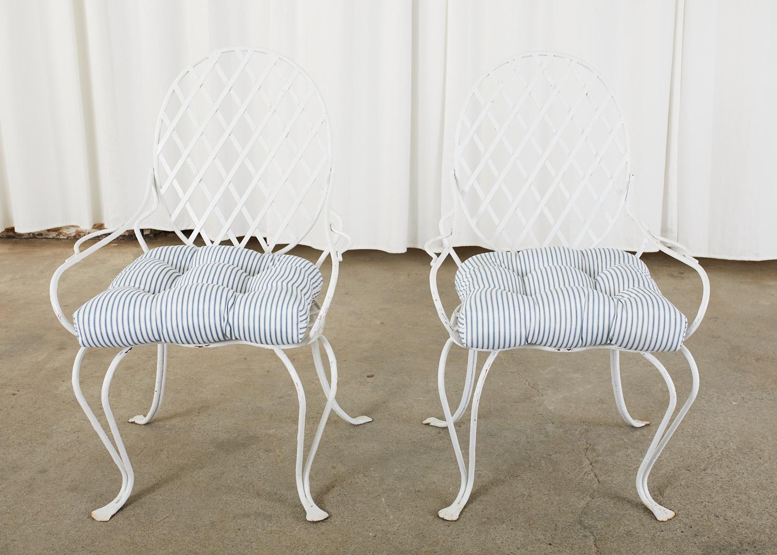 White painted pair of iron patio and garden armchairs by Rose Tarlow Melrose House, CA. The graceful chairs feature a faux bois twig design on the iron frames inset with a woven lattice seat and back. The oval shaped back conjoins to the generous