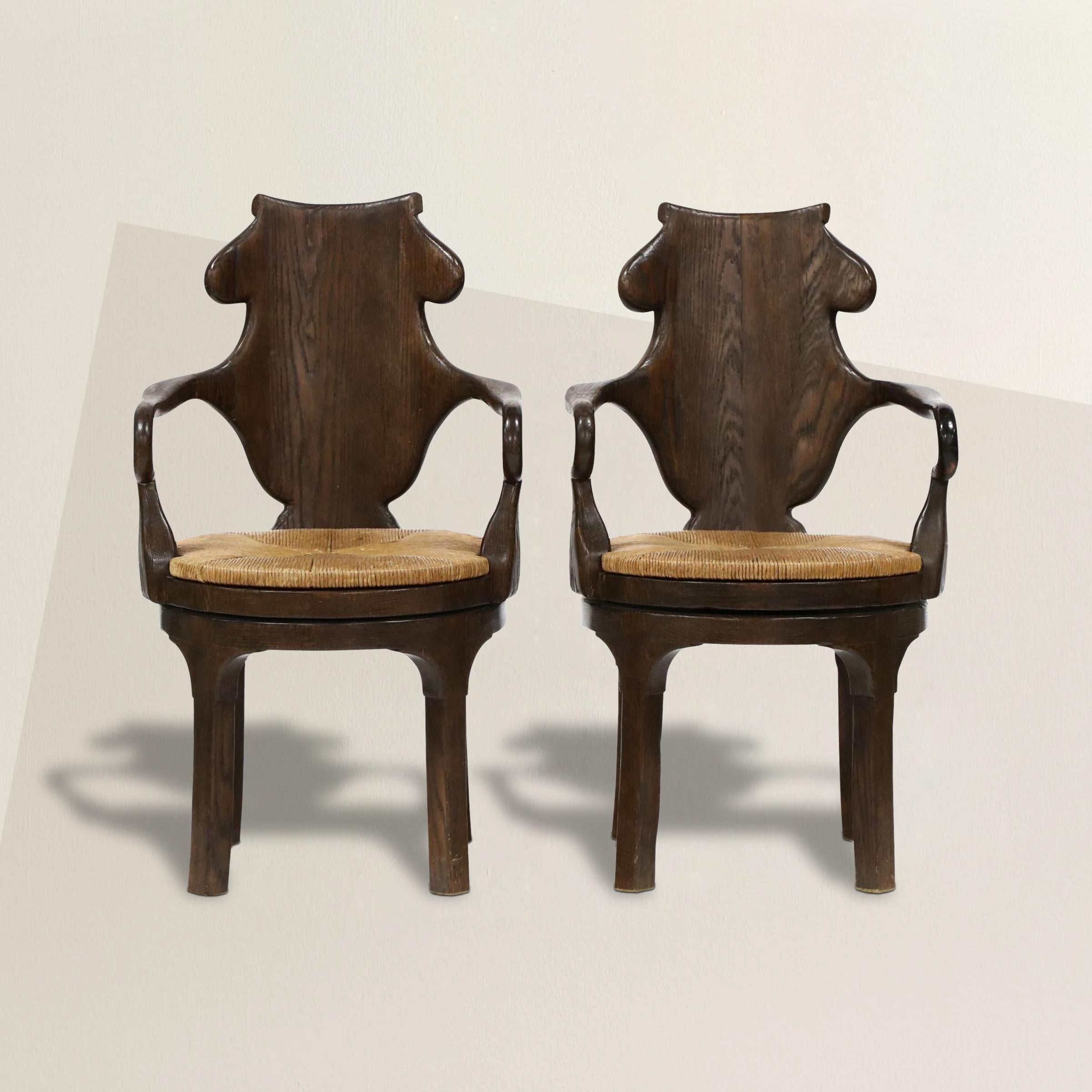 Inspired by 18th century English Georgian chairs, this pair of Rose Tarlow designed Henley oak armchairs feature highly sculptural backs, sensually curved arms, and with removable rush seats that swivel. Perfect dining chairs, but also suitable for