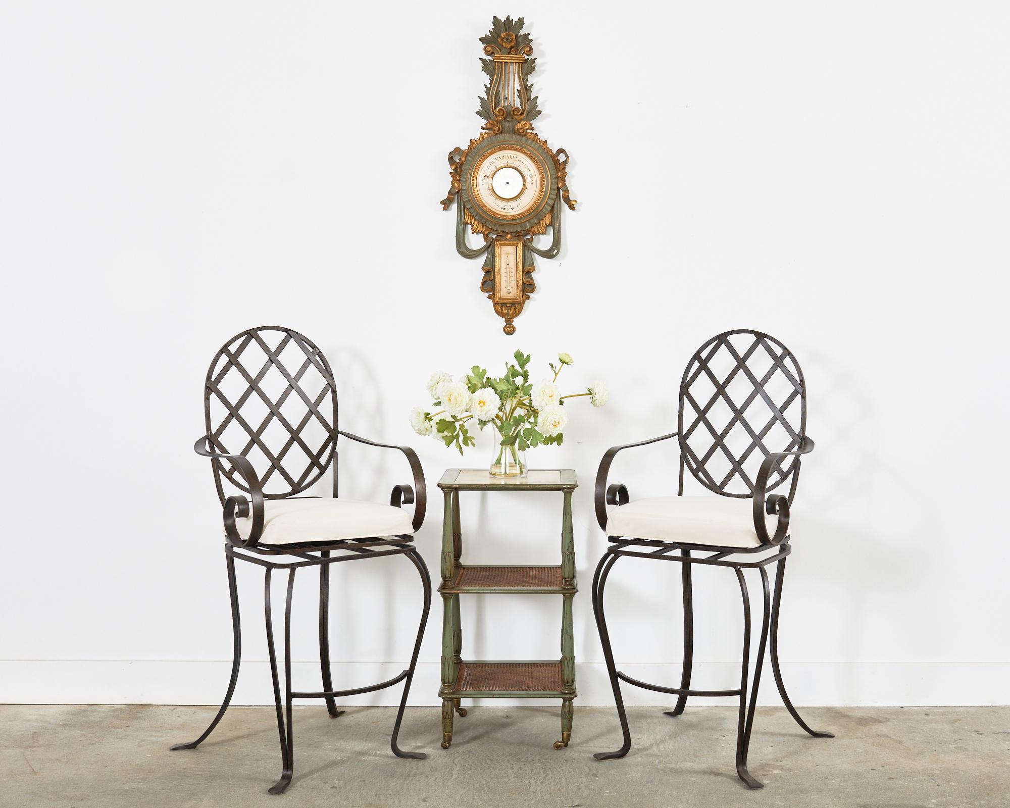 Attractive pair of iron swivel patio and garden bar stools featuring an iron lattice inset seat and back in the style of Rose Tarlow Melrose House. Produced by a foundry in Los Angeles, CA in the style of Mario Papperzini for John Salterini with
