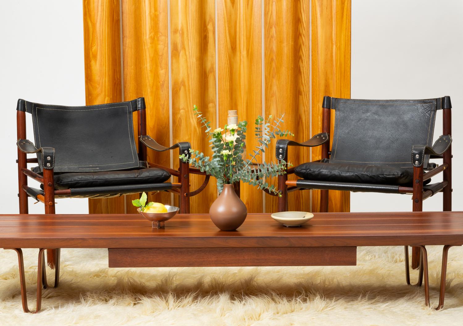 A pair of 'Sirocco' safari chair designed by Arne Norell in 1966 and produced by his eponymous company, in Småland, Sweden. This pair features a solid rosewood frame with pronounced sapwood figuring. Inspired by traditional campaign furniture, as