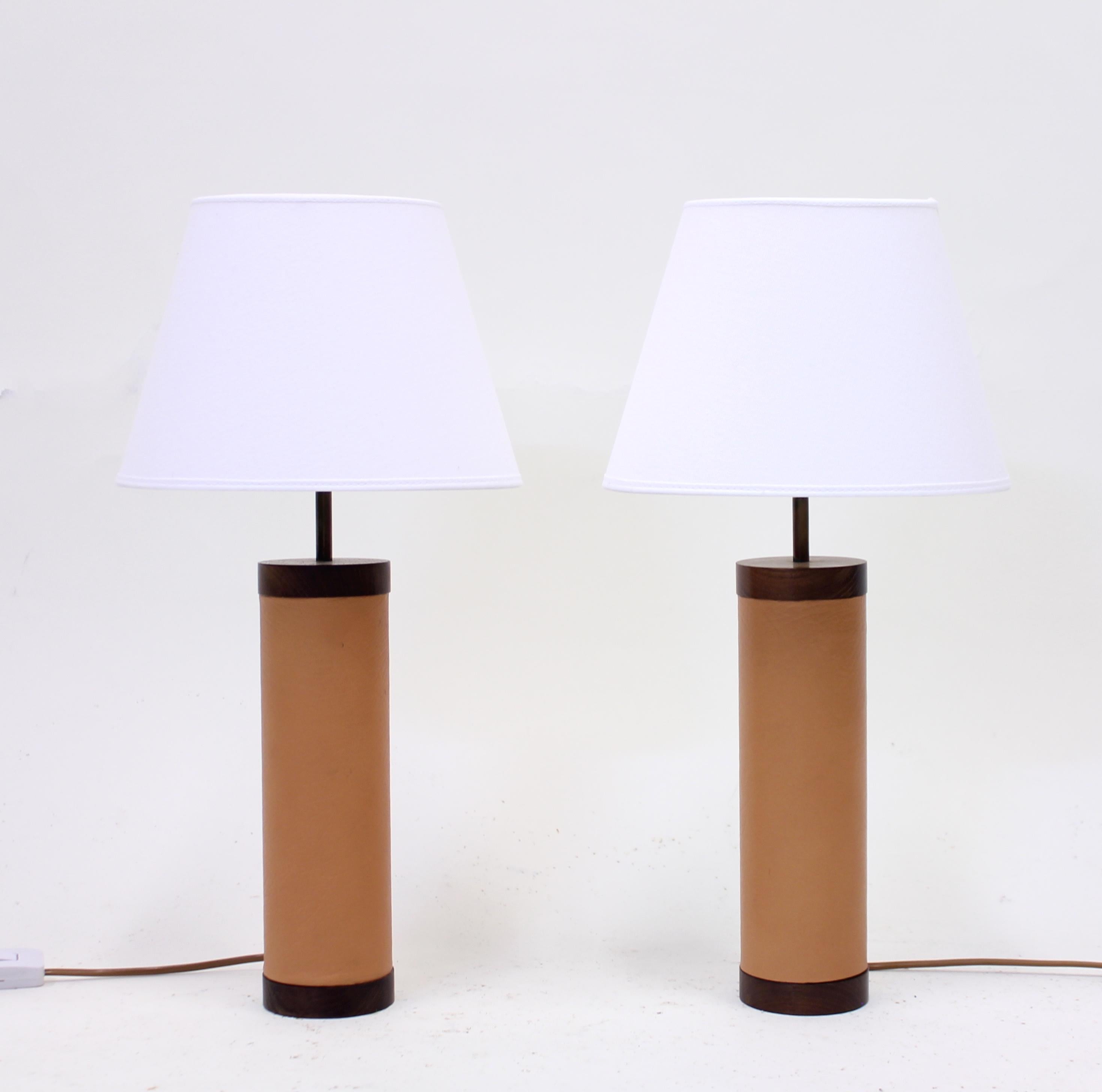 Pair of table lamps from the 1960s in rosewood and light brown leather attributed to Swedish manufacturer Bergboms. New white shades. Very good condition with minimal ware.