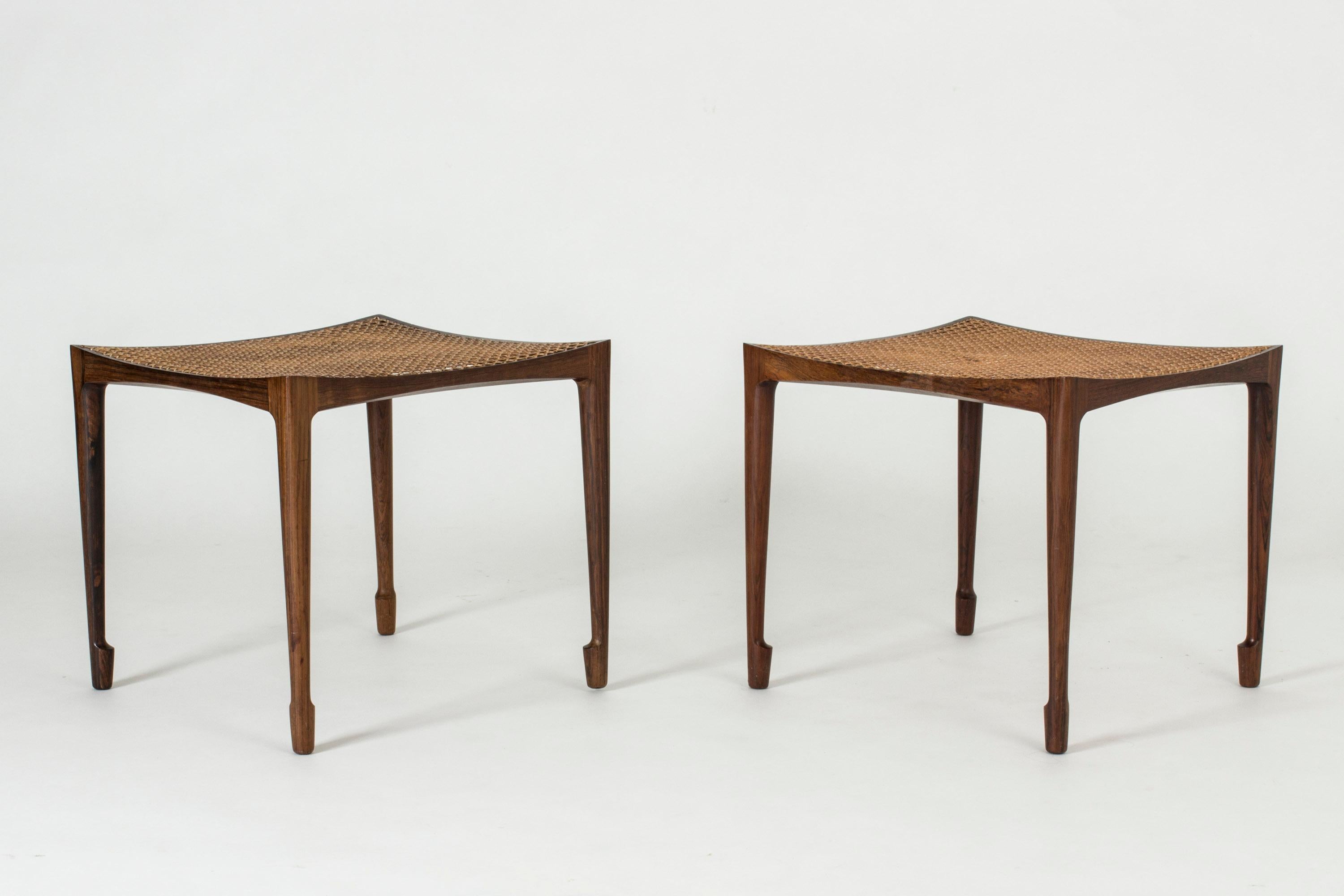 Pair of stunning rosewood and rattan stools by Bernt Petersen. Beautiful, slender design with sculpted legs and seats that are subtly concave.