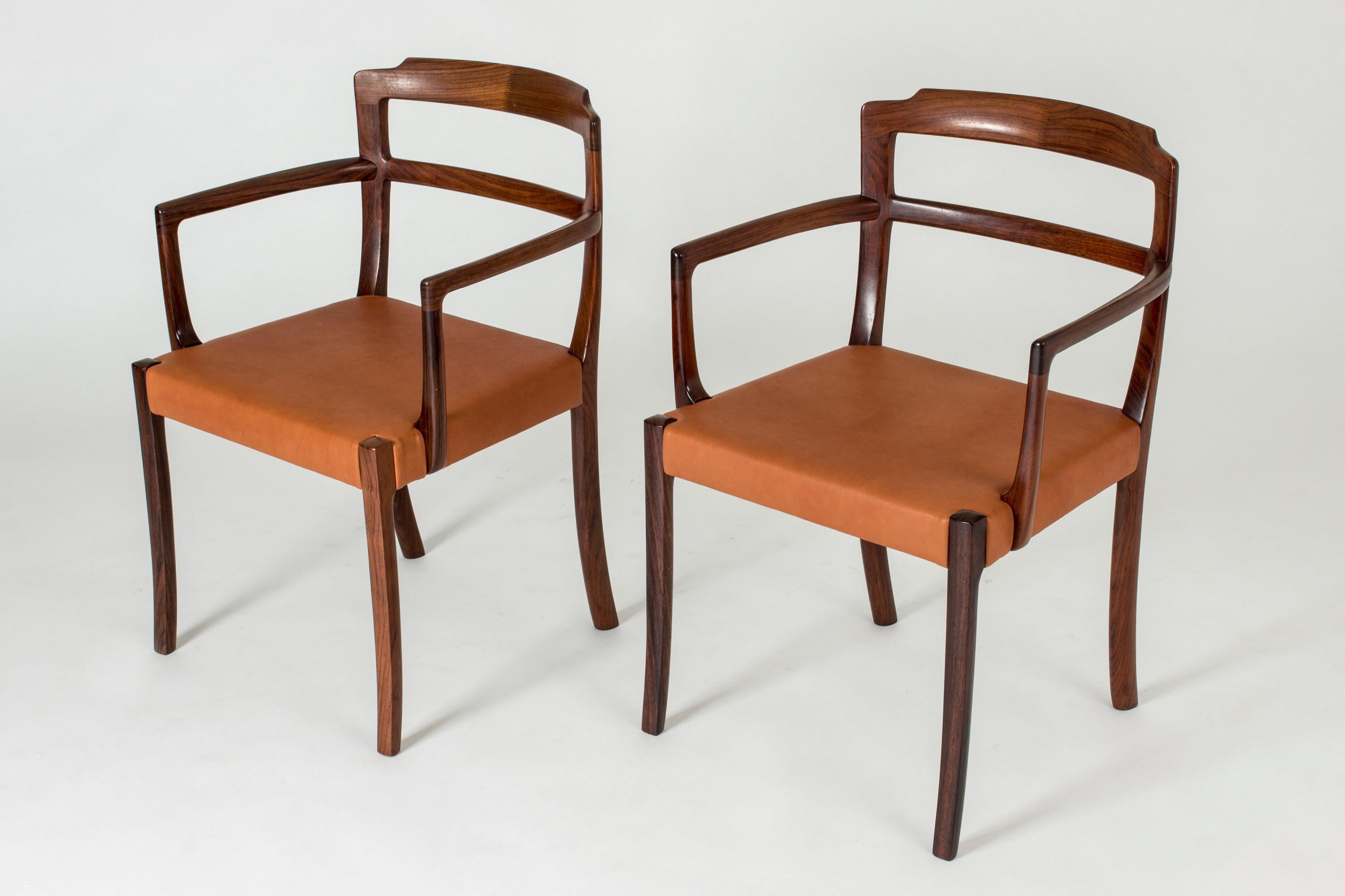 Pair of rosewood armchairs by Ole Wanscher, upholstered with cognac leather seats. Beautifully designed, slender arms and legs.