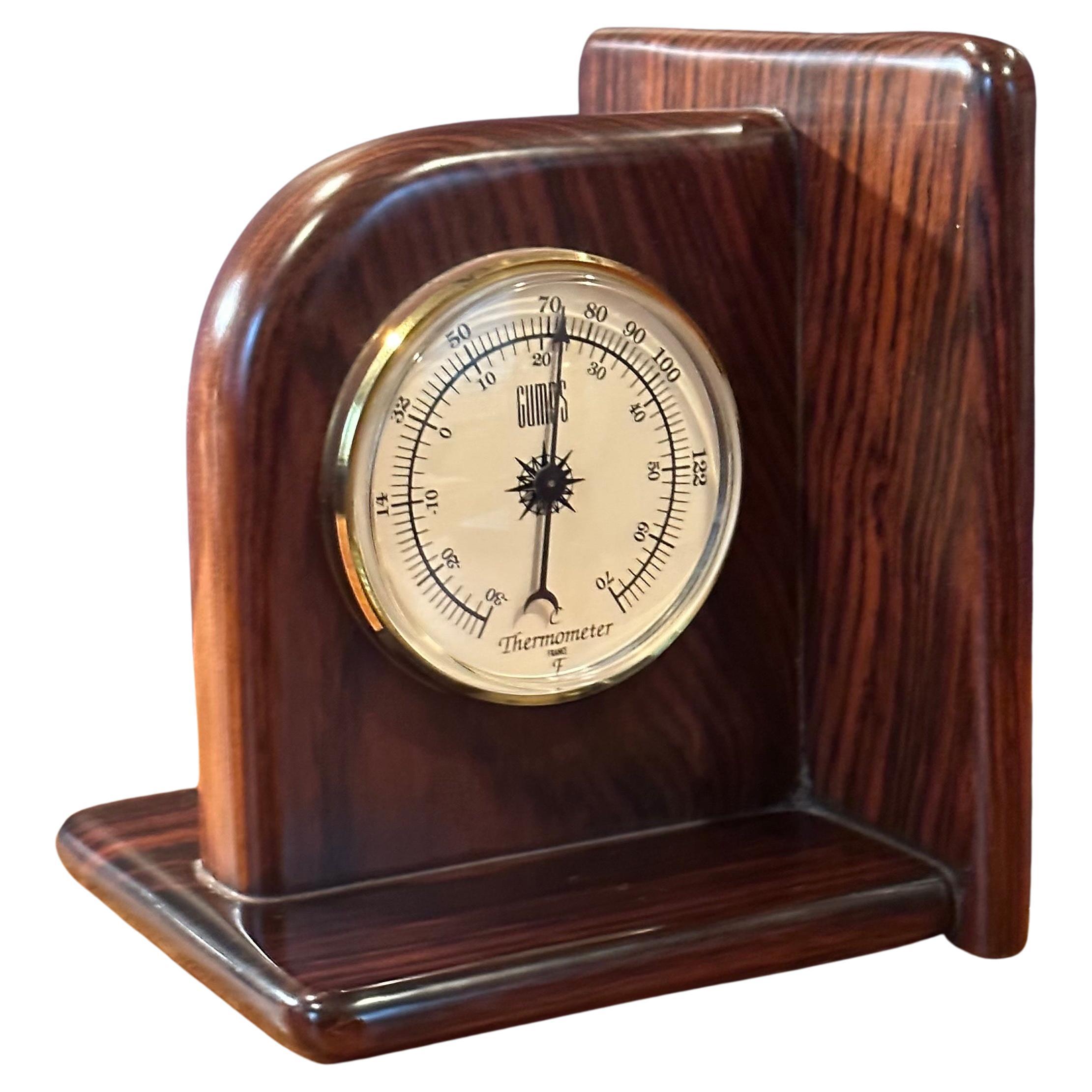 A really nice pair of rosewood bookends with clock and thermometer by Gumps, circa 1990s. This gorgeous rosewood set has wonderful grain patterns and a high quality quartz clock and thermometer which were made in France; the set measures: 13