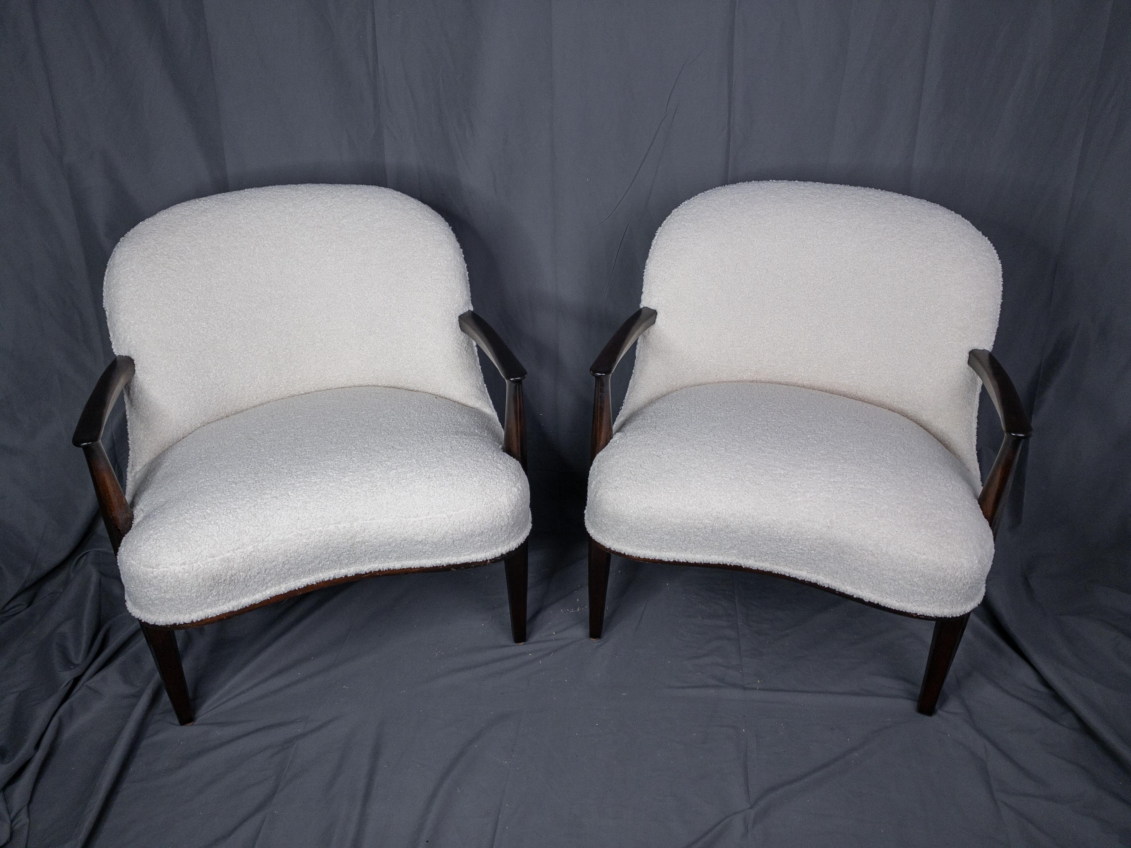 Dieses Paar Lounge-Sessel aus Palisanderholz, drapiert in prächtigem Bouclé-Stoff, ist der Inbegriff von Raffinesse und Komfort. Die mit viel Liebe zum Detail gefertigten Palisanderrahmen weisen eine tiefe, glänzende Maserung auf, die die ihnen