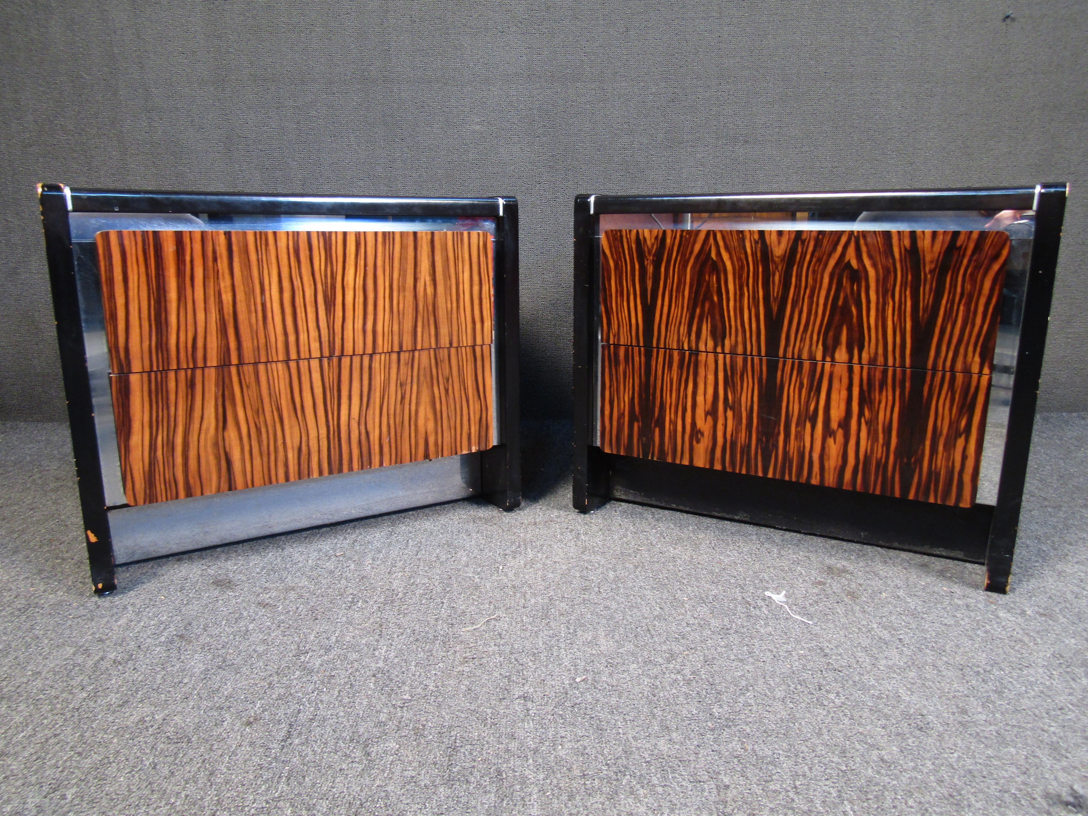 This pair of vintage nightstands by John Stuart includes dovetailed drawers, ebonized surfaces, chrome accents, and radiant rosewood fronts for timeless Mid-Century Modern style. Please confirm item location with seller (NY/NJ).