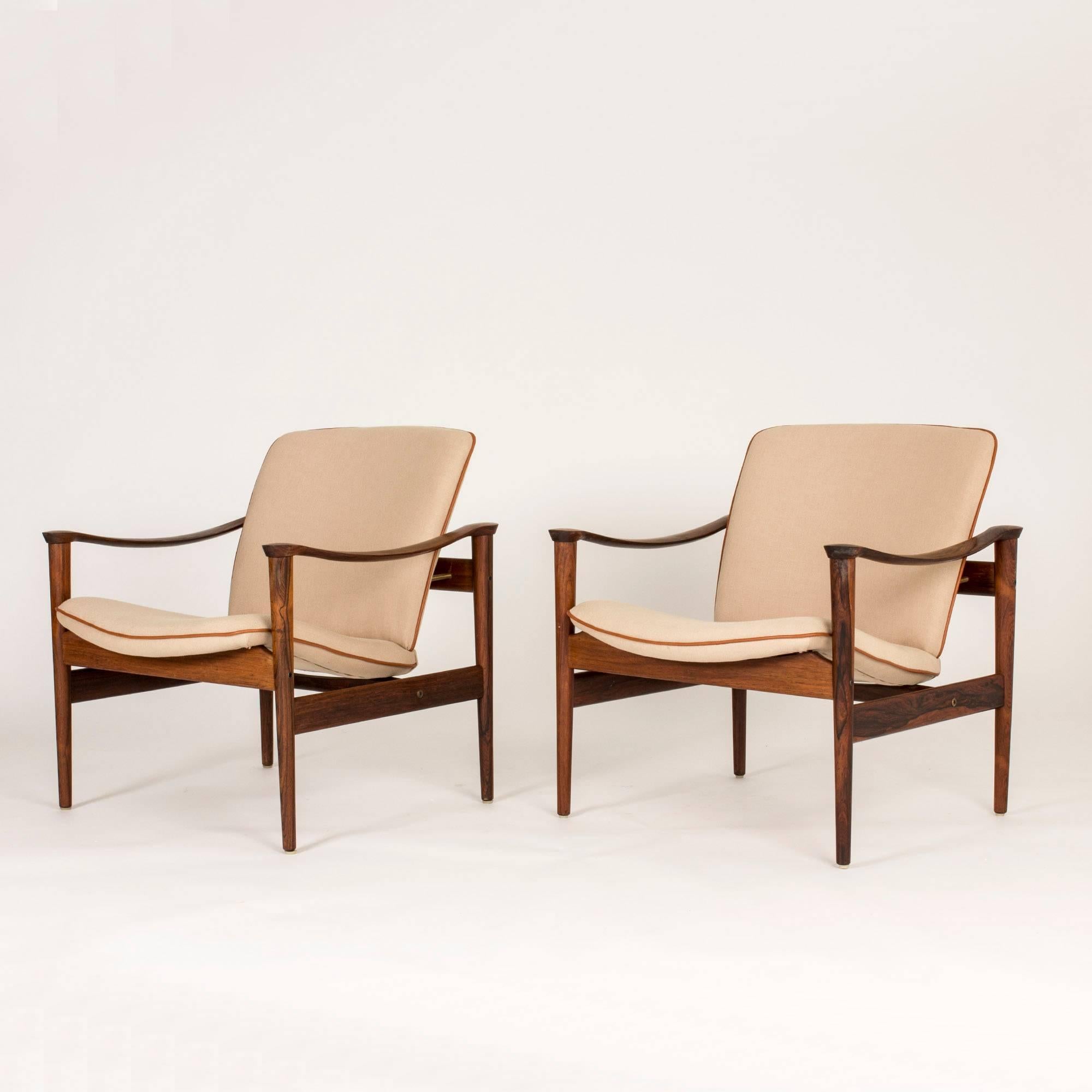 Pair of lounge chairs by Fredrik Kayser with beautiful sculpted armrests. Upholstered with off-white wool fabric with brown leather piping along the edges. Measure: Seat height 42 cm.