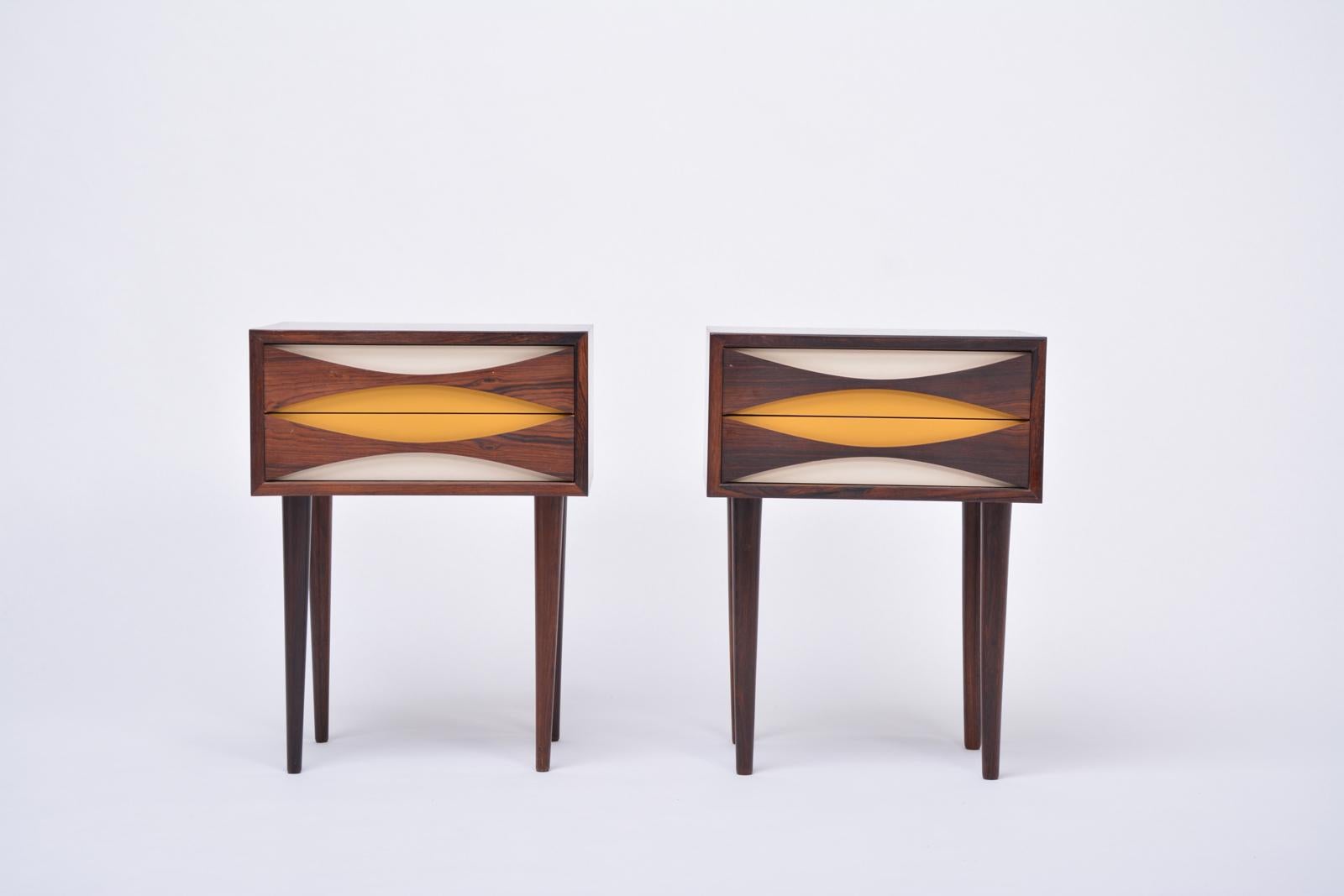 Pair of nightstand cabinets designed by Niels Clausen for NC Mobler in Odense, Denmark. Produced circa 1960s each with two drawers with scalloped pulls and solid tapered legs. Often misattributed to Arne Vodder. Fronts have been lacquered.
