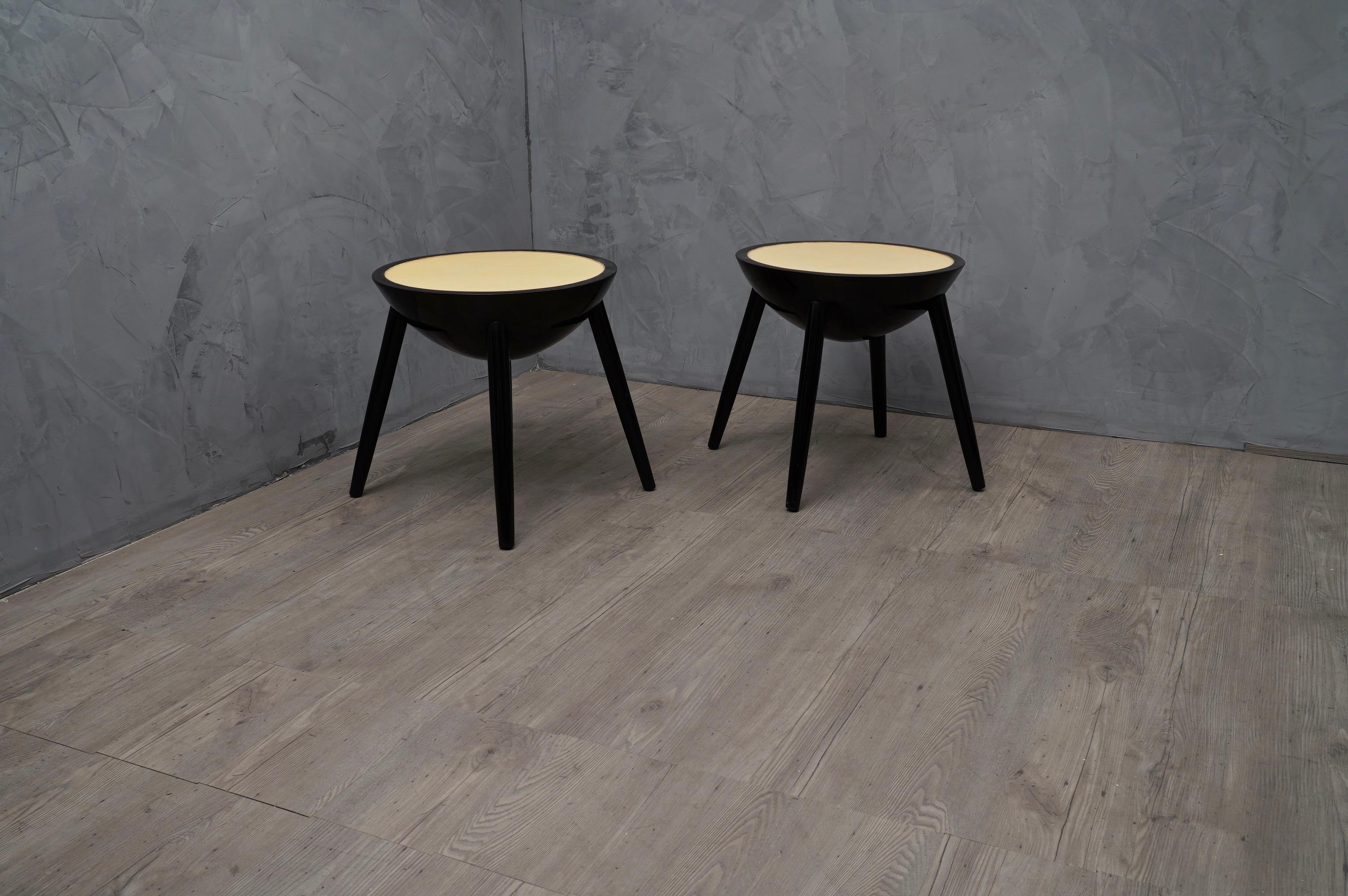 Pair of Italian Art Deco side tables, of the first half of the 20th century.

Round side tables with top covered in parchment leather or goat skin, and polished with transparent resin. All around the top runs a polished edge in black lacquer.