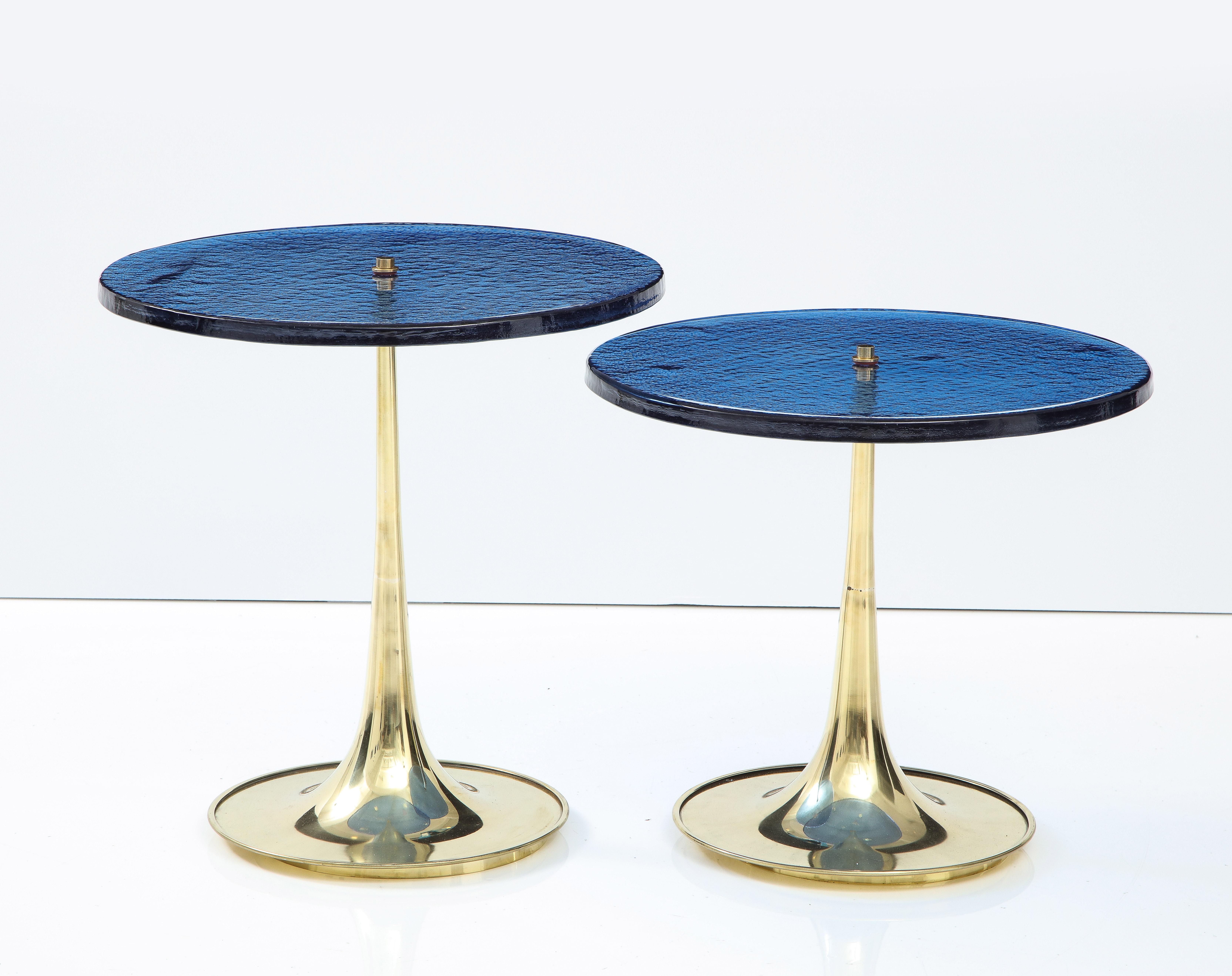 Pair of round deep blue murano glass and brass martini or side tables, Italy, 2022. Hand-casted 1 inch thick, solid deep blue colored Murano round glass sits atop a hand -turned trumpet-shaped brass base. Modern flat top brass finial screws the
