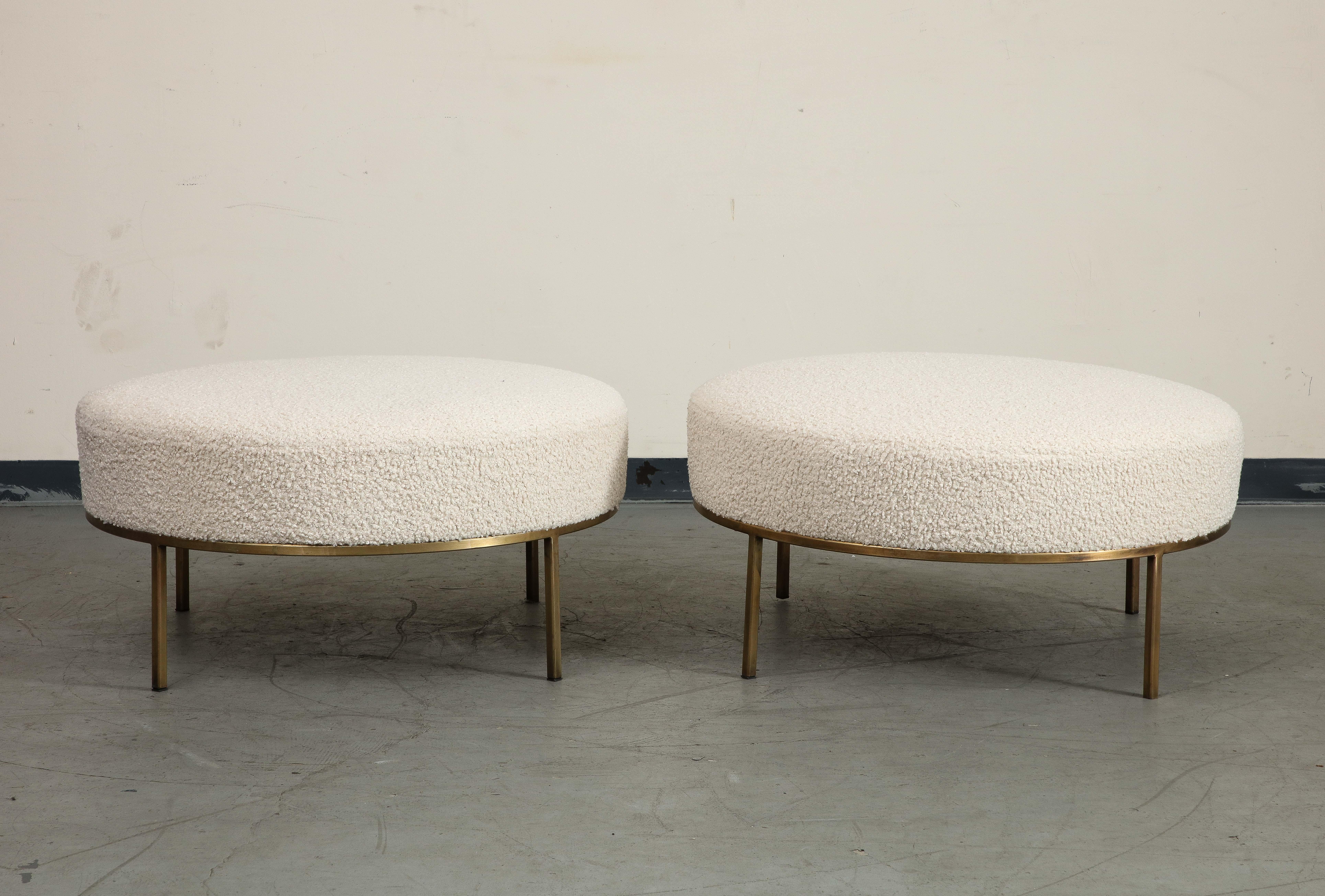 Pair of contemporary Chautauqua Round Ottomans by Amber Lewis, handmade in Los Angeles. Featuring bone bouclé upholstery on an elegant Minimalist brass base with a custom patina finish that will age beautifully and build character over time. Like