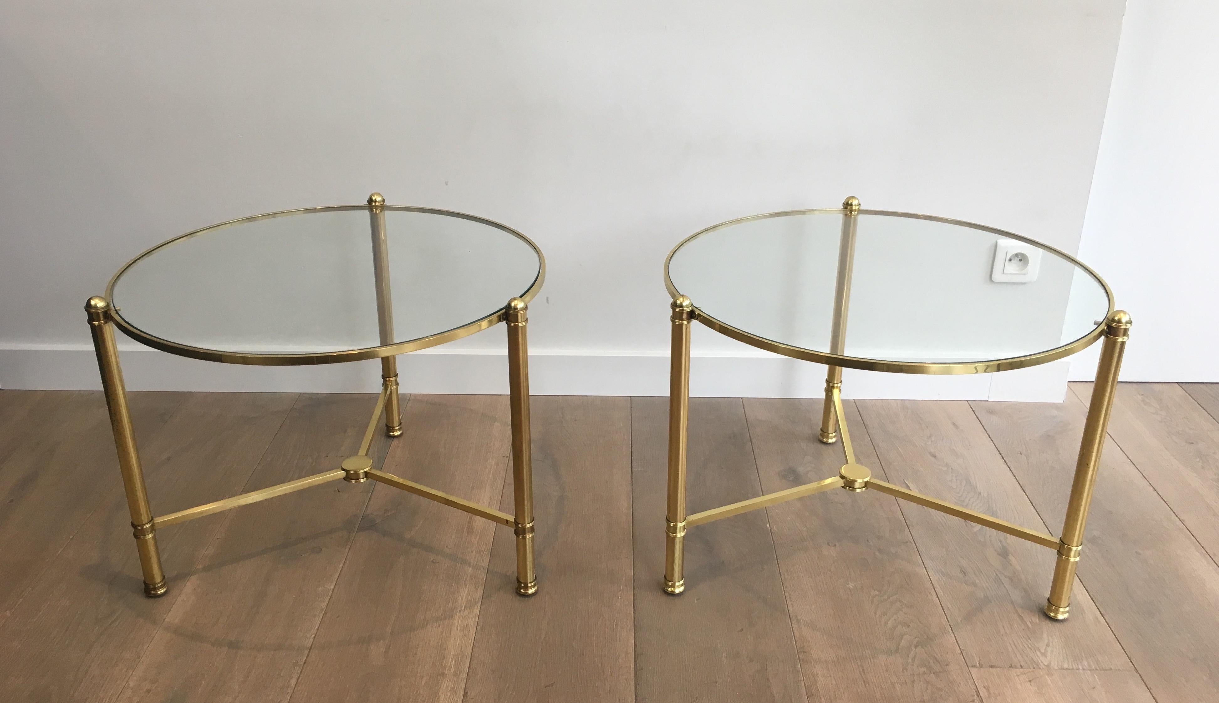 This pair of round side tables is made of brass with clear glass tops. This is a French work, circa 1970.