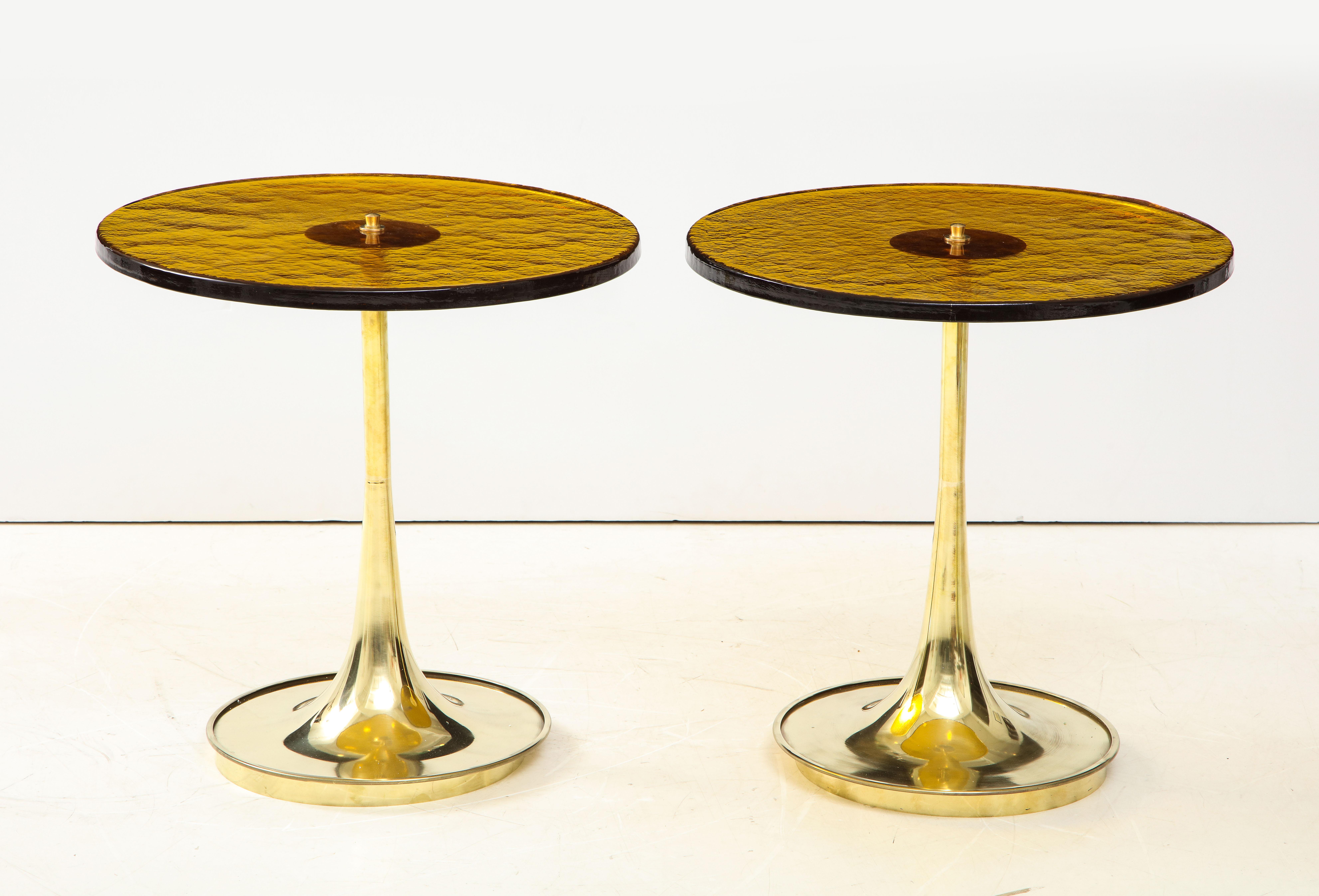Pair of round bronze murano glass and brass martini tables, Italy. Hand-casted thick and solid bronze colored murano round glass sits atop a hand -turned trumpet-shaped brass base. Modern flat top brass finial screws the glass top to the brass base.