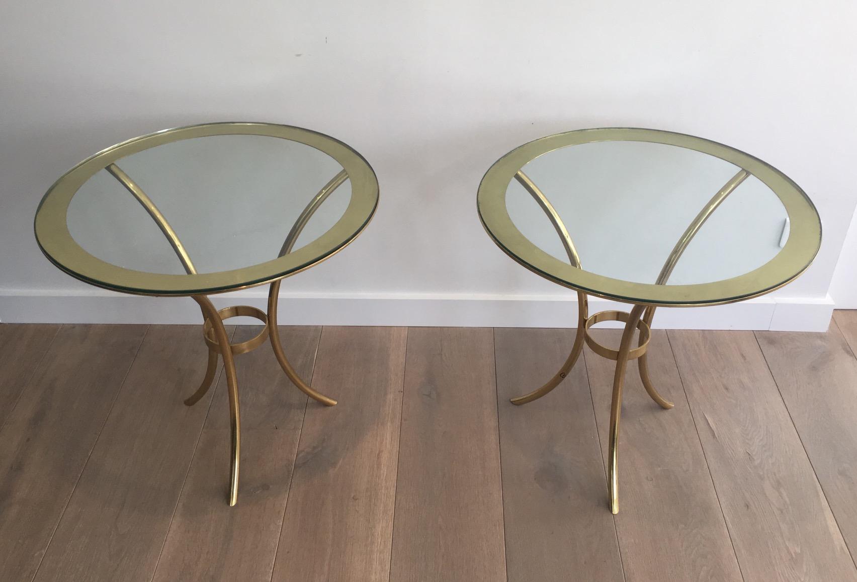 This pair of round gold gilt brass side tables have a glass top fixed on the top circle. They are very elegant. This is an Italian work, circa 1970.