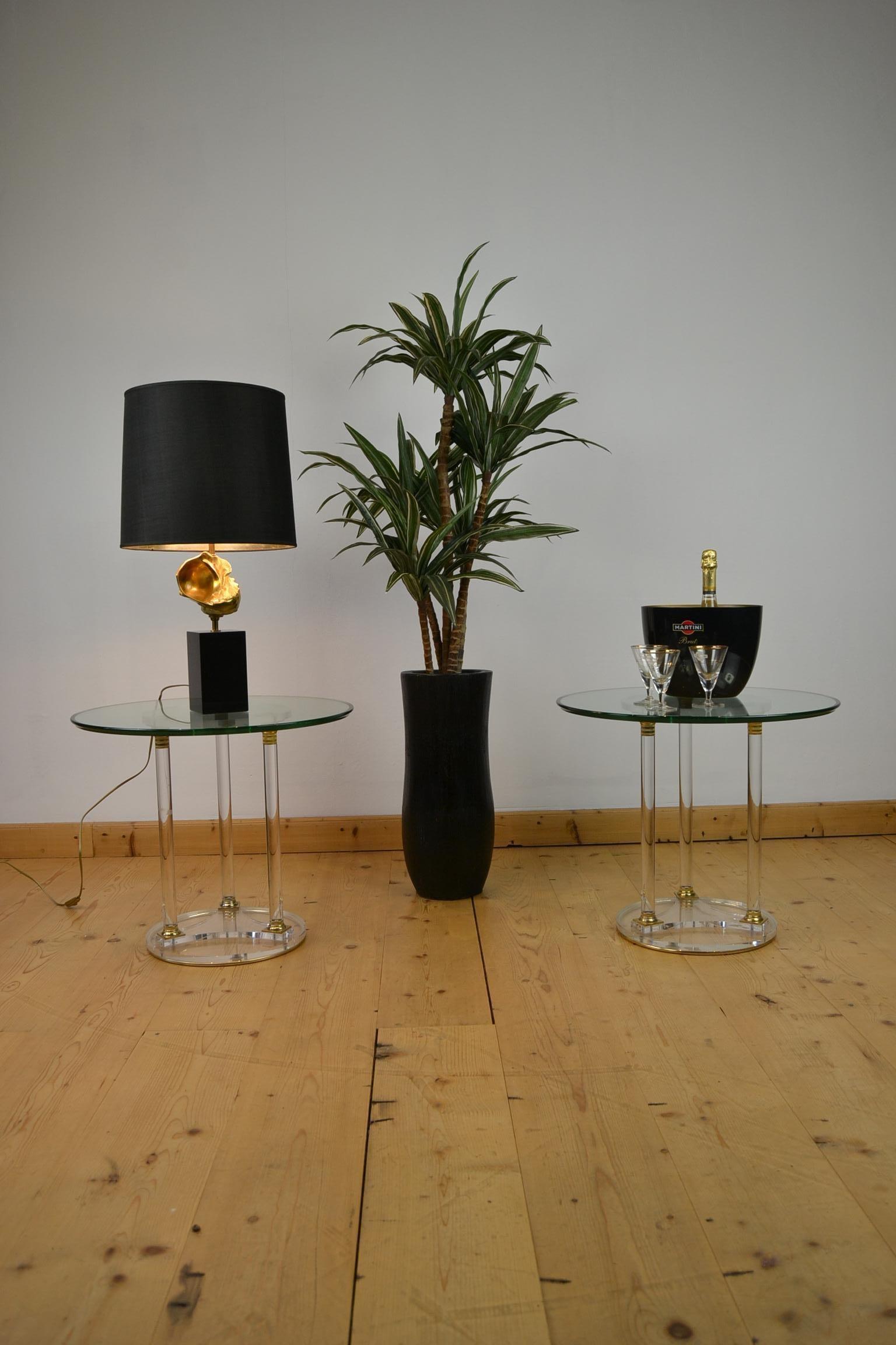Pair of round side tables consisting of Lucite with brass base with a thick glass table top.  These French circular drink tables - coffee tables or cocktail tables date from the 1970s.  The bases have each 3 pillars with beautiful and stylish brass
