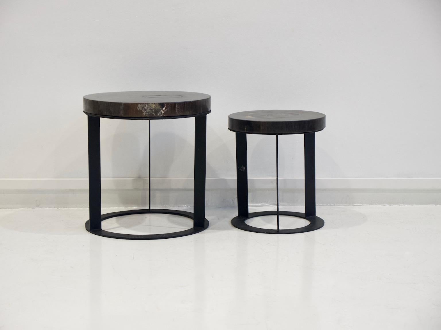 Set of two side tables with round black metal base and dark petrified wood top. Large measures: height 46.5 cm, diameter 44.5 cm. Small: height 40 cm, diameter 34 cm.