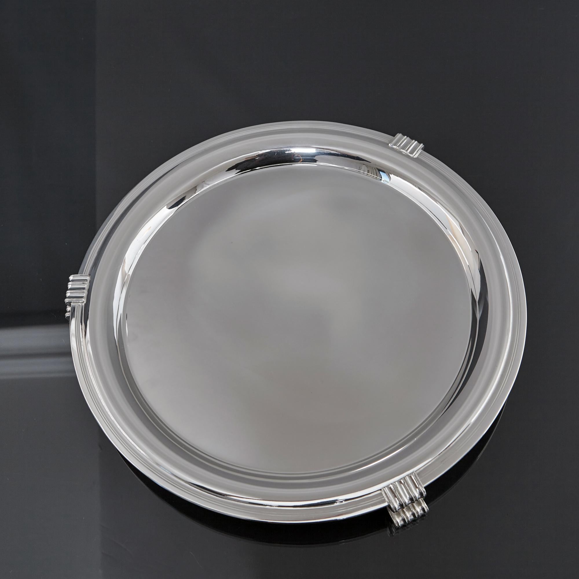 This pair of stylish mid-century silver salvers are round with flared rims and an attractive turned edge. Each plain, undecorated silver salver is mounted on three Art Deco style feet with a fluted curved form. They make an ideal pair of display or