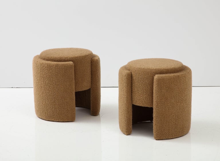 Pair of Round Sculptural Poufs or Stools in Camel or Taupe Boucle handcrafted in Florence, Italy, 2023 by a master carpenter. Center floating round padded seat is surrounded by two half round padded platforms that serve as legs. Upholstered in an