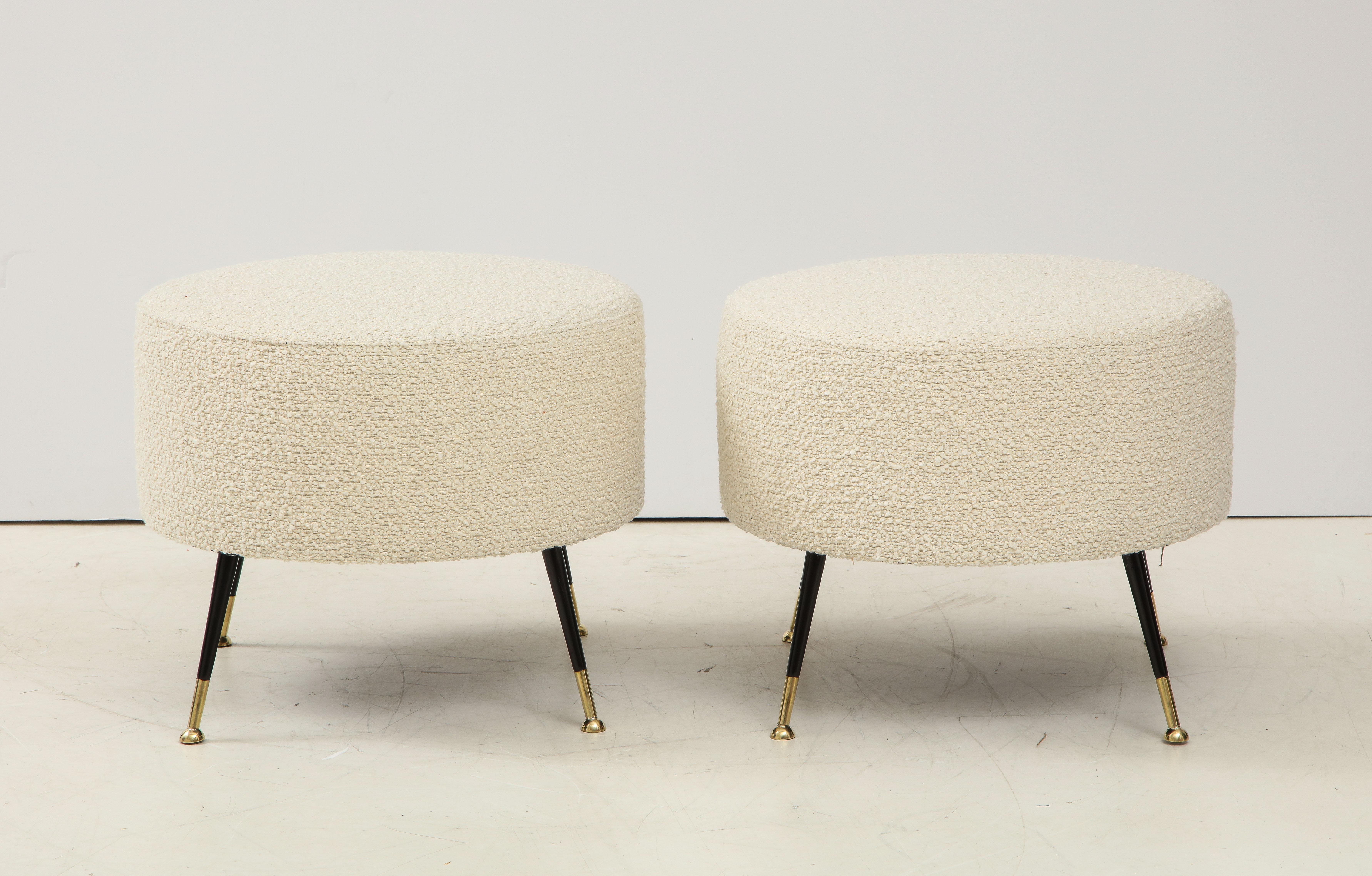 This pair of round stools or poufs were hand made in Florence, Italy, by a master furniture artisan. Round seats in imported Ivory Boucle fabric with black enamel and brass legs. This pair of stools or poufs are on display at the Gallery at 200 Lex
