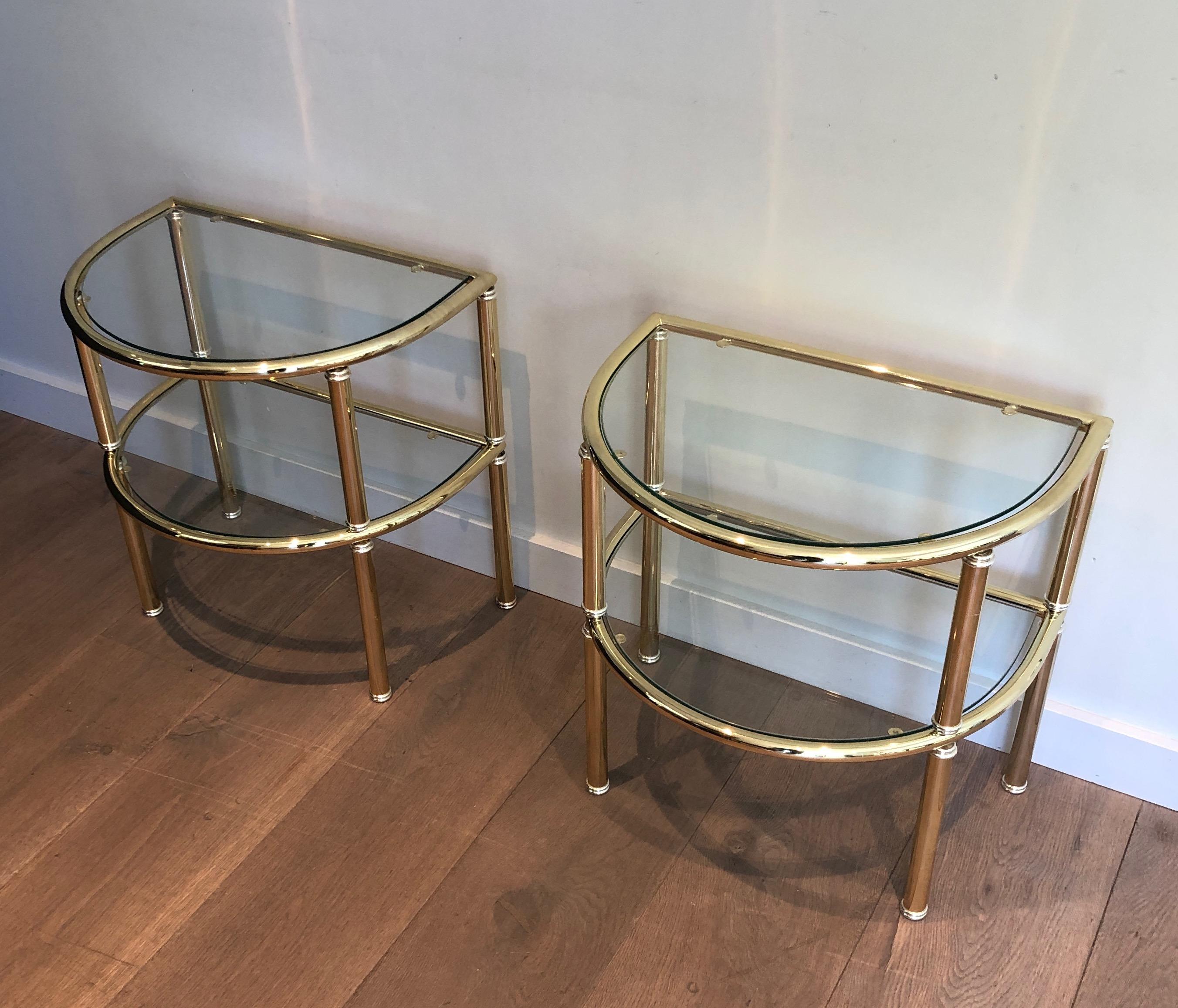 This very nice pair of rounded side tables is made of brass and silvered brass with glass shelves. This is a French work. Circa 1970