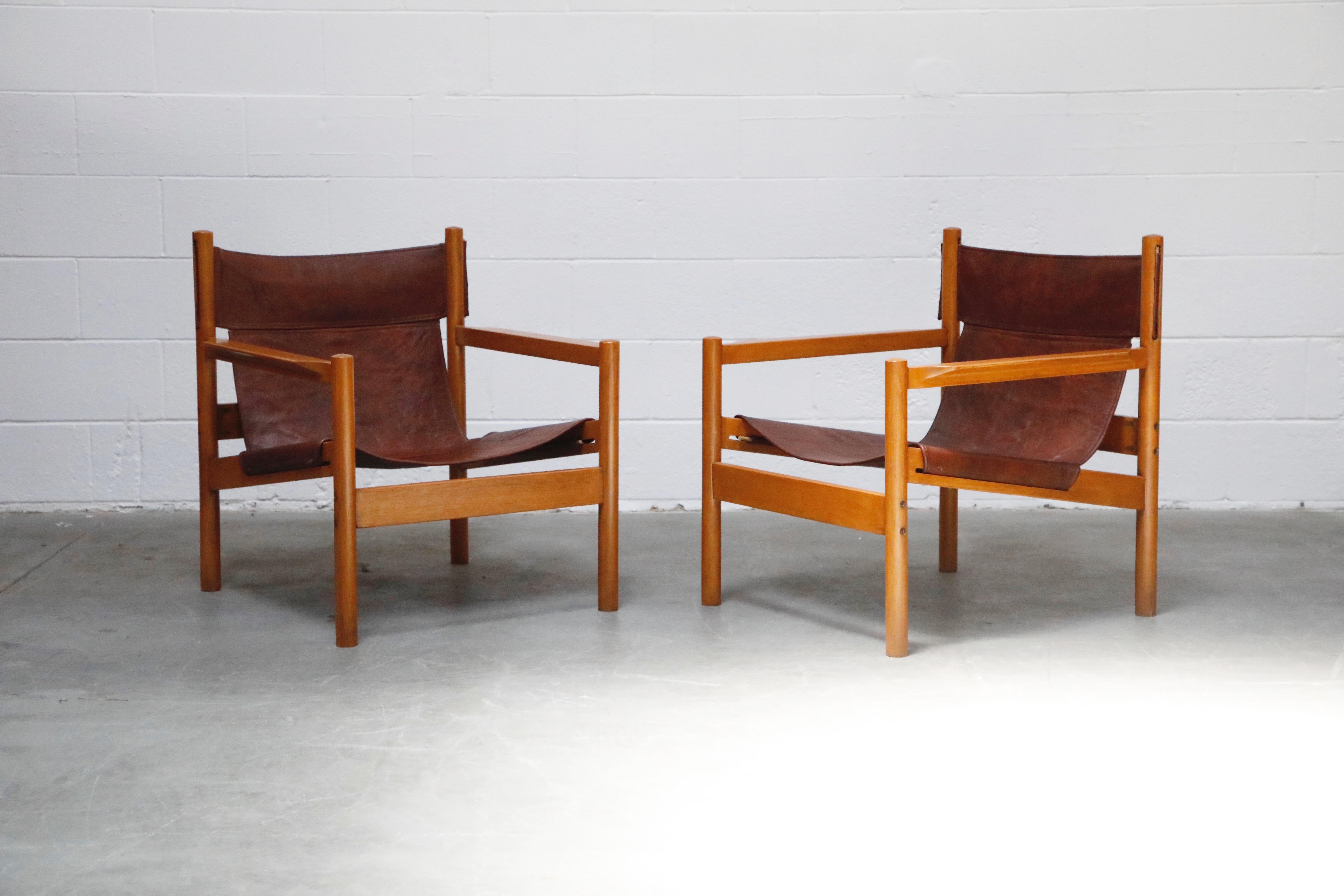 This incredible pair of 'Roxinho' safari style lounge chairs by Michel Arnoult, circa 1960s Brazil, feature stitched leather sling seats and seat backs, with Brazilian hardwood frames. Such casual refinement, perfect for a laid-back look while