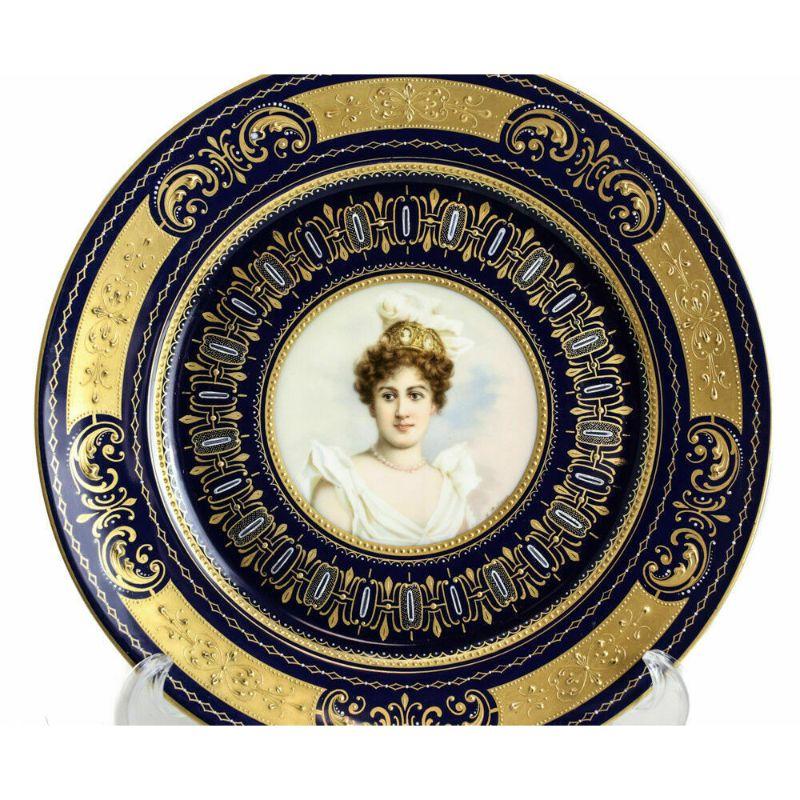 Pair of Royal Vienna porcelain hand painted portrait plates, circa 1900.

Beautiful cobalt blue ground with golden encrusted leafy scroll accents. Central images depict two beautiful brown-haired women in royal white wheat sheaves. Artist signed