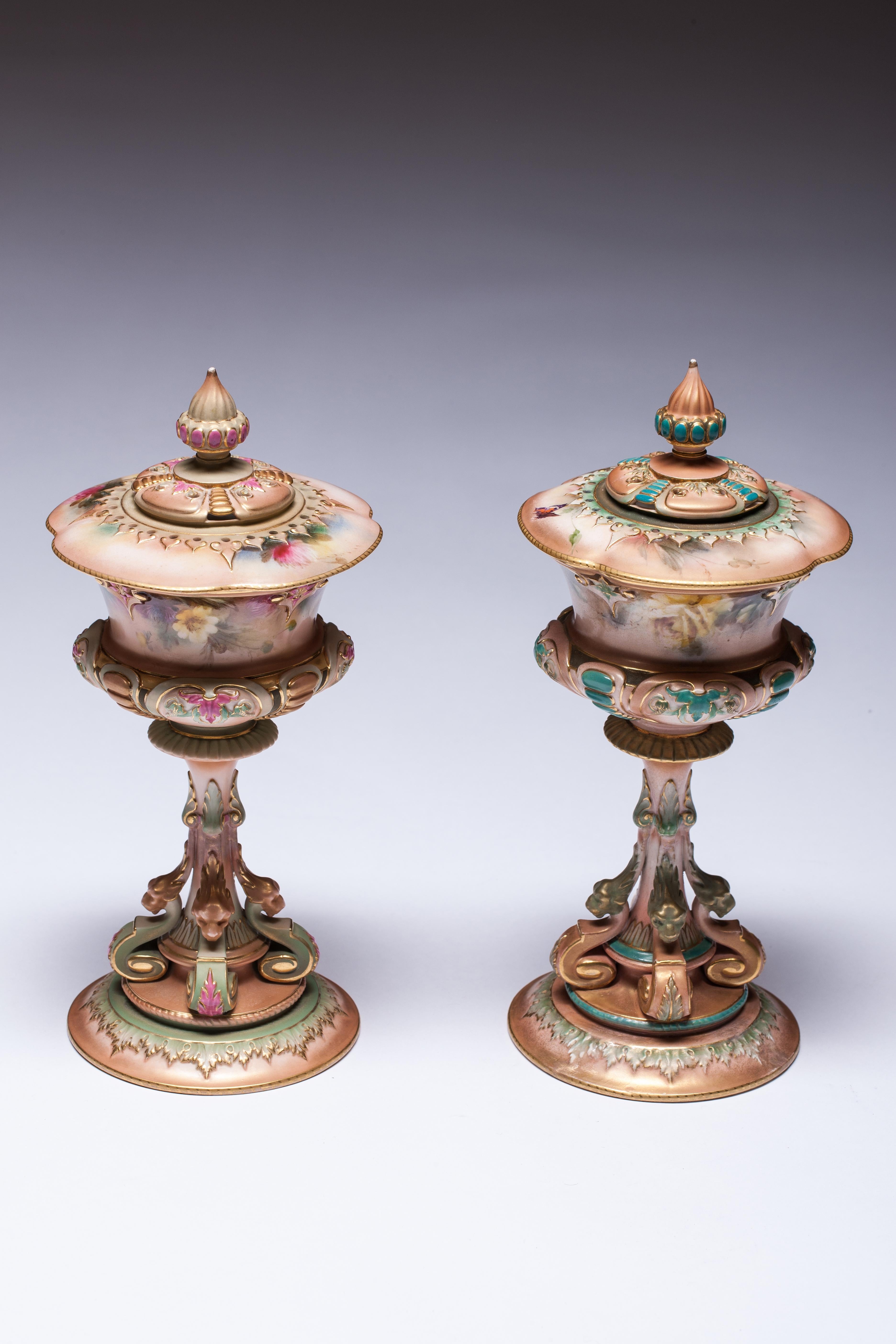 Pair of Royal Worcester Hadley style goblet vases with hand-painted floral decoration and figural scroll pedestal base.

 
