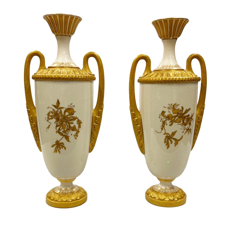 A fine quality pair of late 19th century Worcester porcelain vases, each with wonderful Ivory ground and gilded decoration, depicting classical motif moldings and twin handles to each, the bodys with flowing foliate and floral hand painted detail.