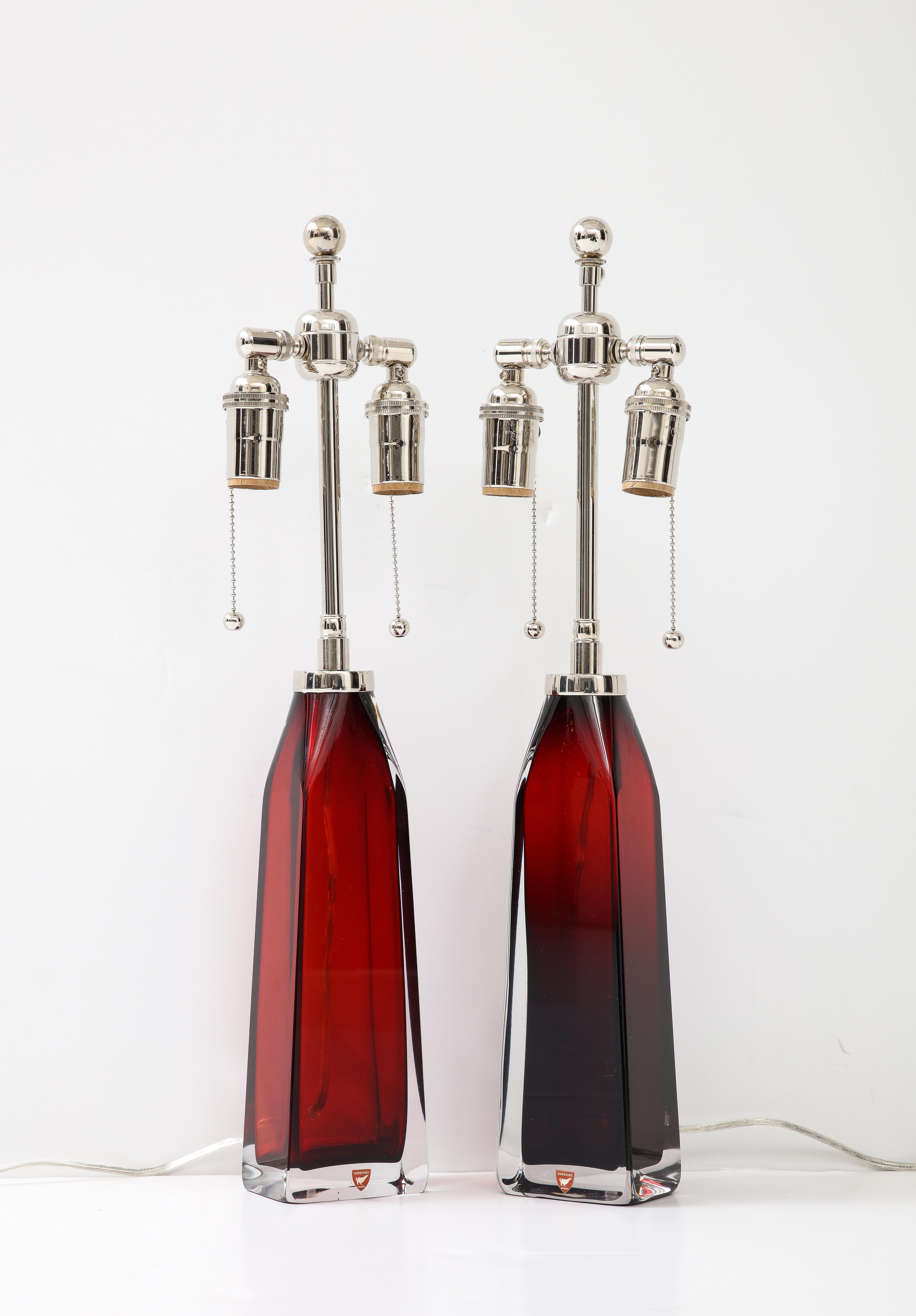 Beautiful pair of Ruby Red crystal lamps by Nils Landberg for Orrefors.
The lamps have been Newly rewired with adjustable polished Nickel double 
clusters that take standard size light bulbs.
The height to the top of the glass is 12