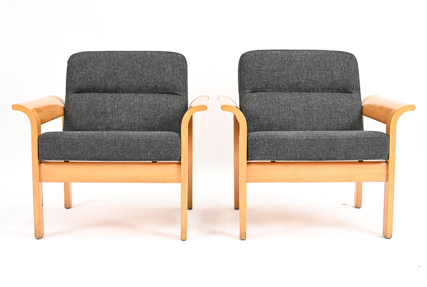 A pair of Danish mid-century lounge chairs designed by Rud Thygesen for Magnus Olesen / Botium, marked with labels underneath. Featuring beechwood frames with flared armrests and gray wool upholstery. c. 1970's.