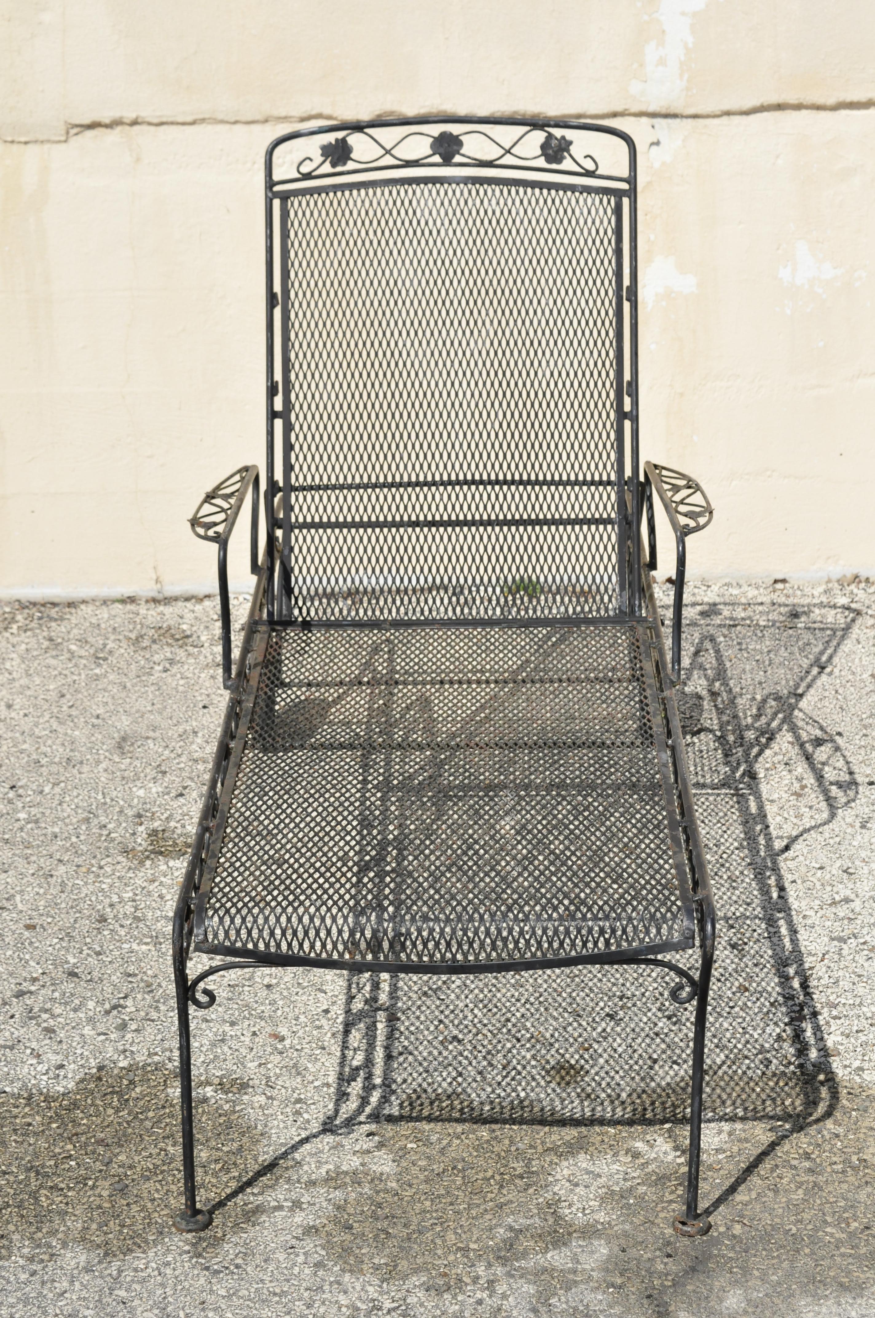 Pair of Russell Woodard patio garden reclining wrought iron chaise lounge chairs. Item features scrolling maple leaf design, metal mesh back and seat, adjustable/reclining back, rubber wheels, wrought iron construction, quality American