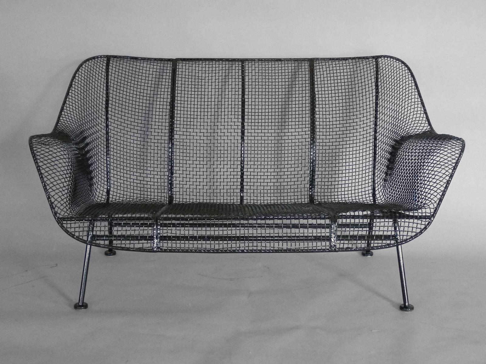 Russell Woodard Sculptura series pair of wrought iron settees with steel mesh seats. Properly restored finished in gloss black powder coat. New foot glides added. Cool and comfortable.