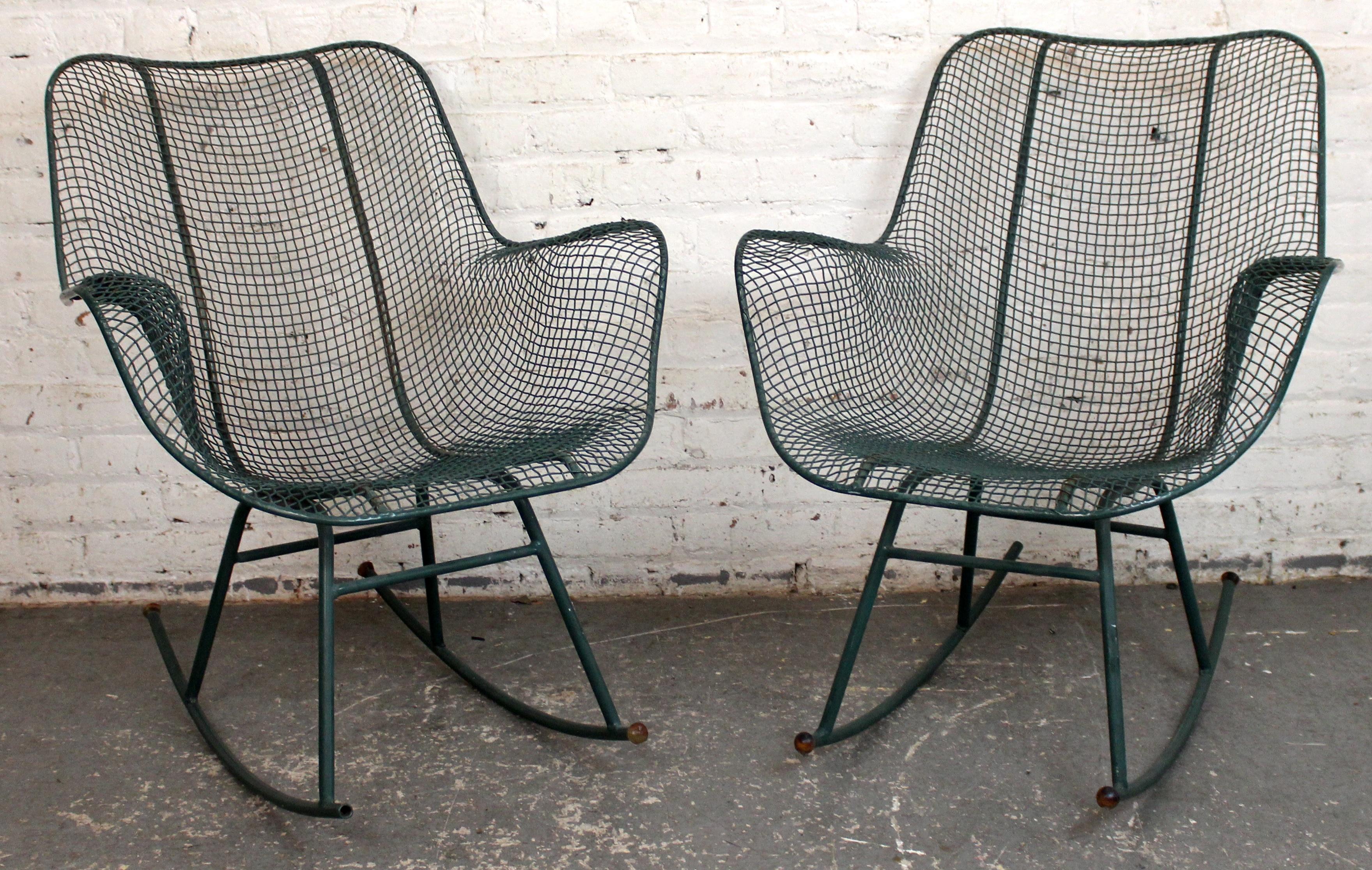 Iconica coppia di poltrone a dondolo in ferro battuto della metà del secolo scorso di Russell Woodard, con il caratteristico design a rete scolpita e l'originale finitura verde. Queste sedie eleganti e resistenti offrono comfort e stile, perfette