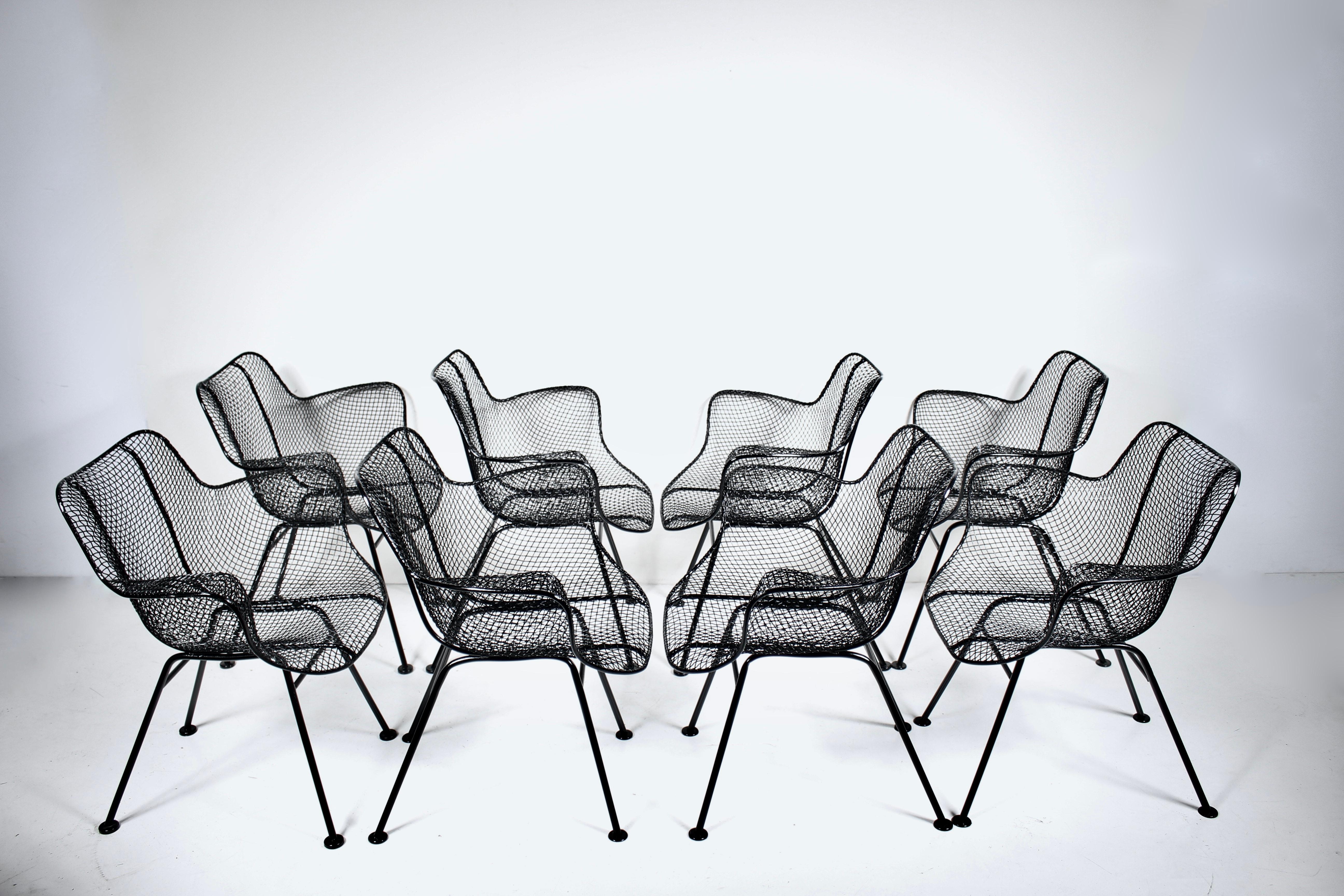 Ensemble original de 8 fauteuils Russell Woodard en fer noir et fil de fer déployé. Structure en fer forgé, assise et dossier ergonomiques en maille métallique noire sculptée, pieds plats. Places assises à l'intérieur et à l'extérieur. Classique.