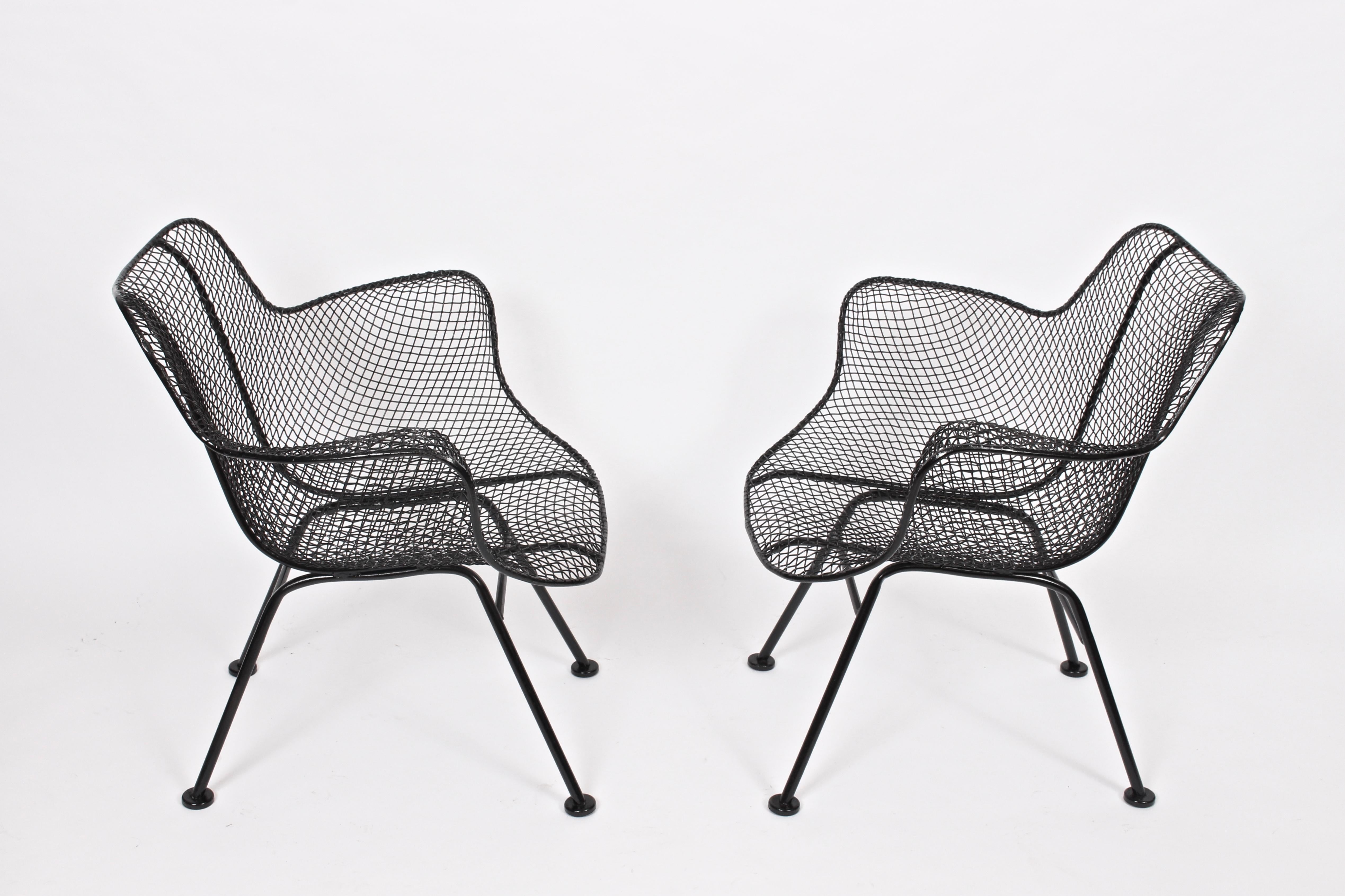 Pair of original Russell Woodard black wrought iron and wire mesh patio armchairs. Featuring a lower wrought iron framework with sculpted black wire mesh. Relaxed. Comfort. Indoor outdoor seating. Professionally sandblasted and painted in high gloss