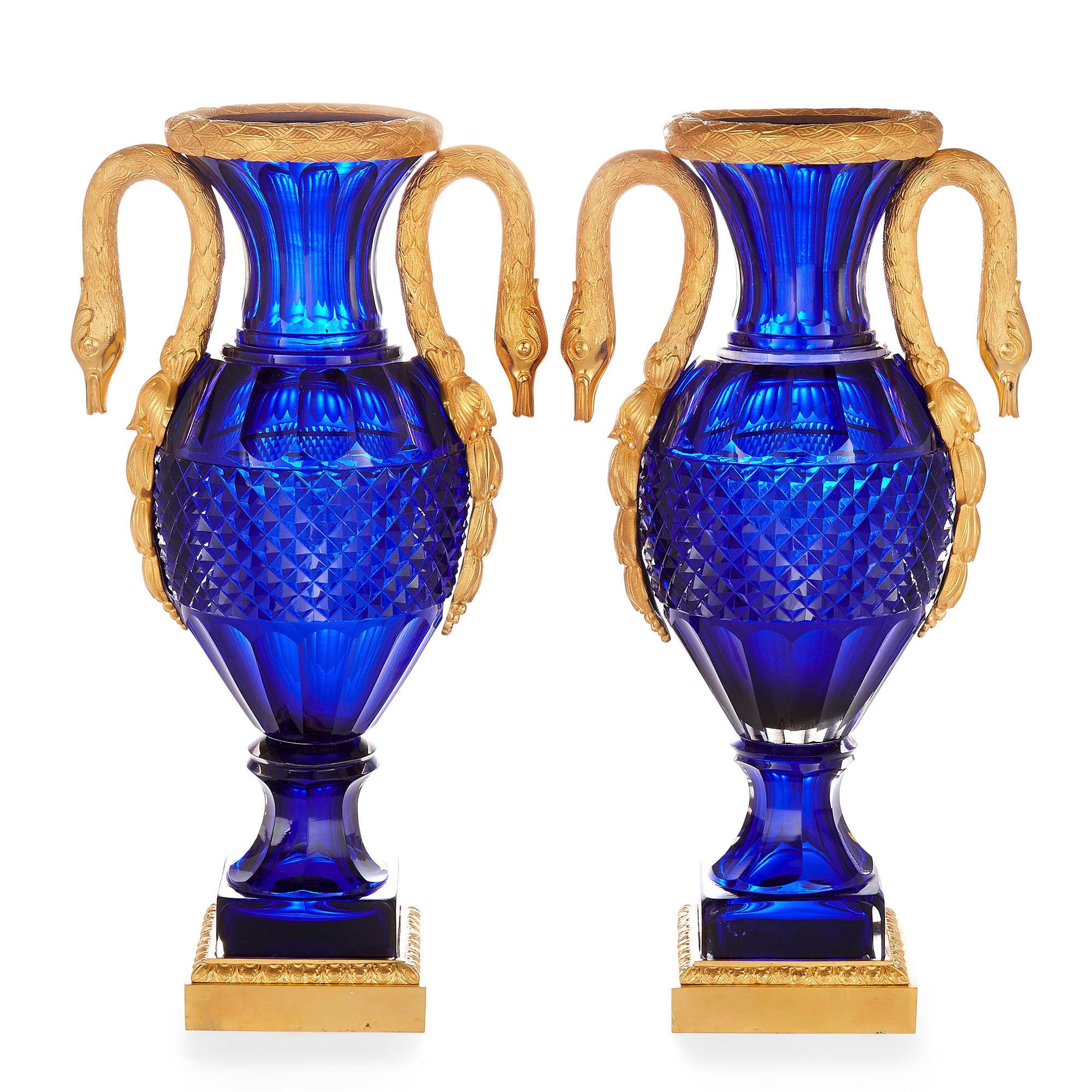 Pair of Russian cut blue glass and gilt bronze vases
Russian, 20th century
Measures: Height 38cm, width 20cm, depth 13cm

Each vase in this pair of Russian neoclassical vases has an ovoid cobalt blue coloured cut glass body and a flared neck.