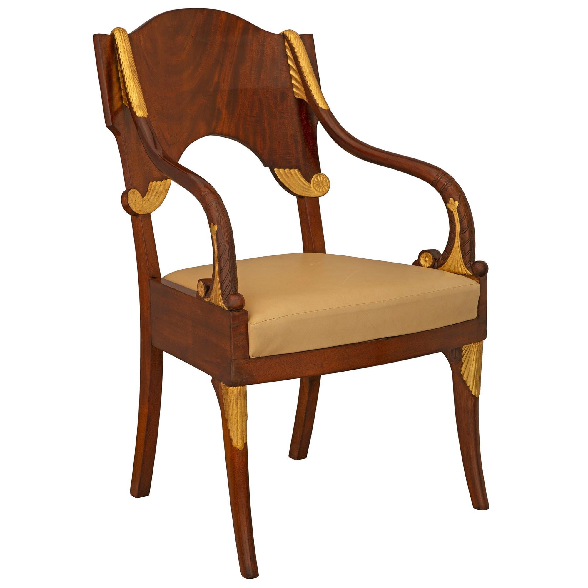 An exceptional and extremely unique pair of Russian mid 19th century neo-classical st. Mahogany and giltwood armchairs. Each chair is raised by elegantly curved legs with beautiful giltwood foliate accents at each corner. The arms each display